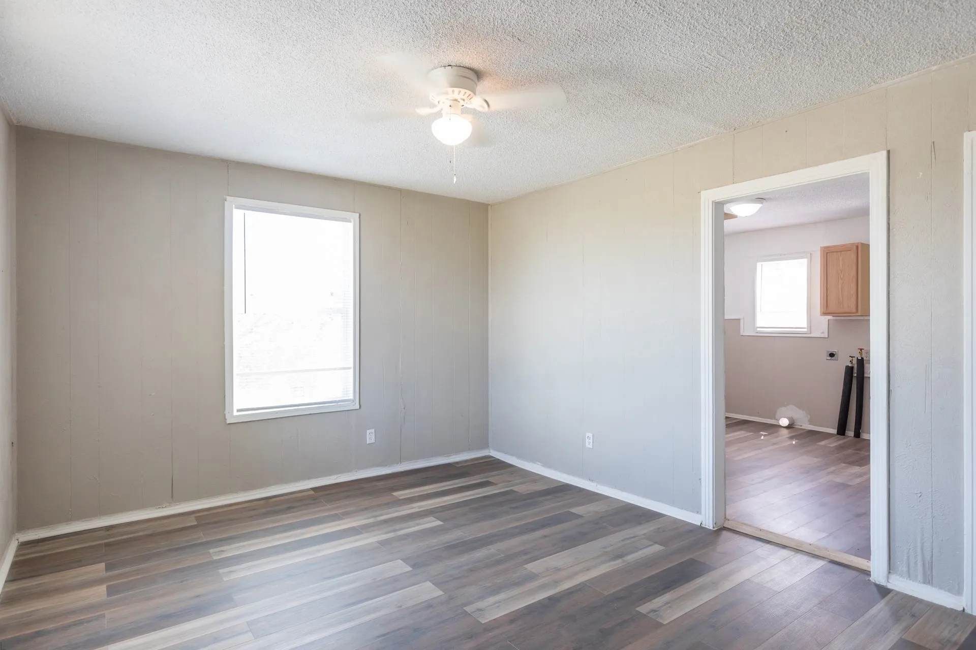 Wood-finish flooring, ceiling fan with light fixture, and a window providing natural light