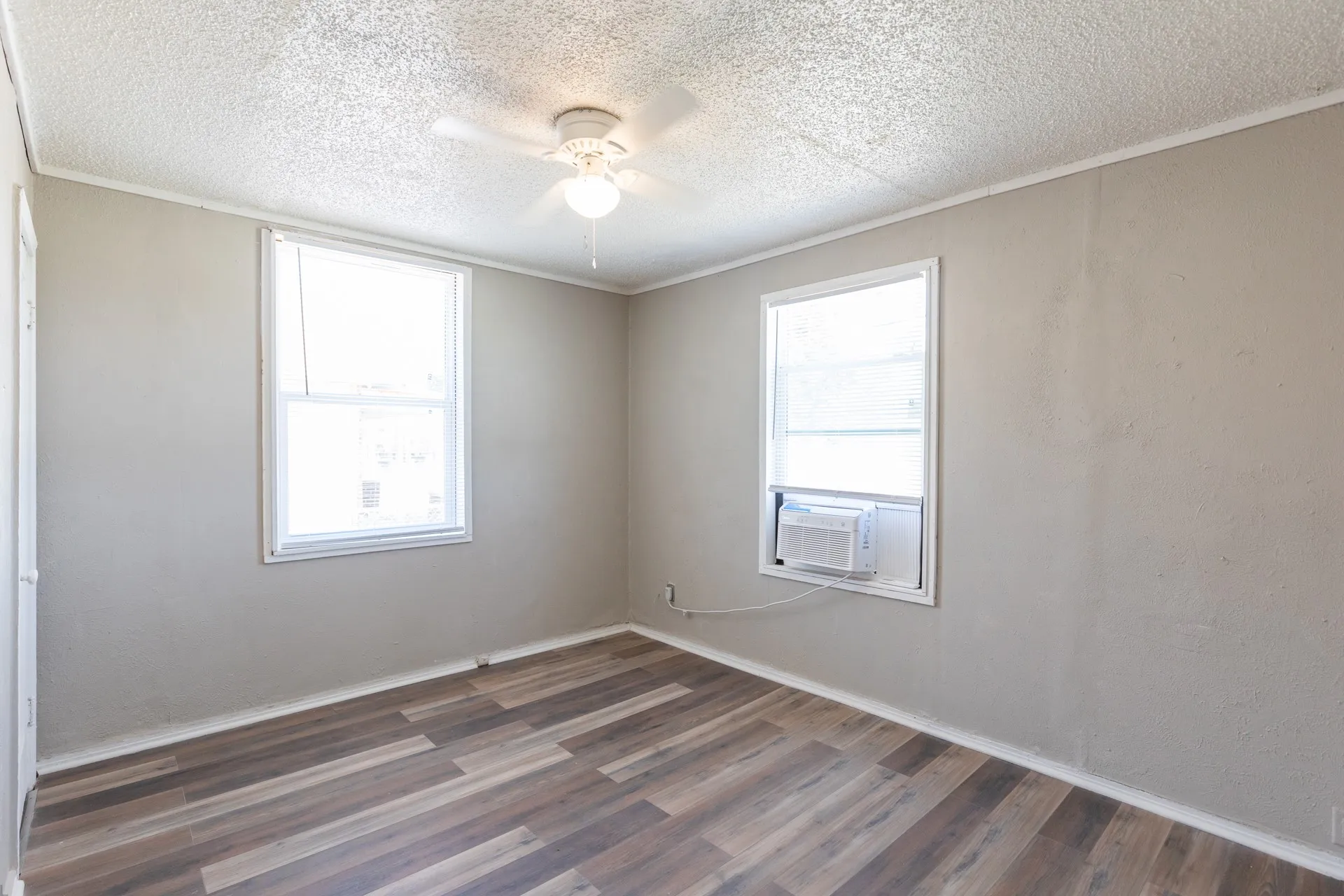 Wood-finish flooring with neutral wall tones and a ceiling fan