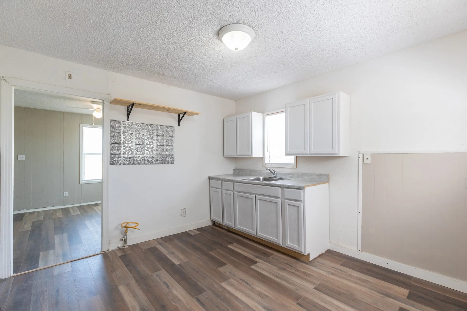 Wood-finish flooring, white cabinetry, integrated sink, and overhead lighting