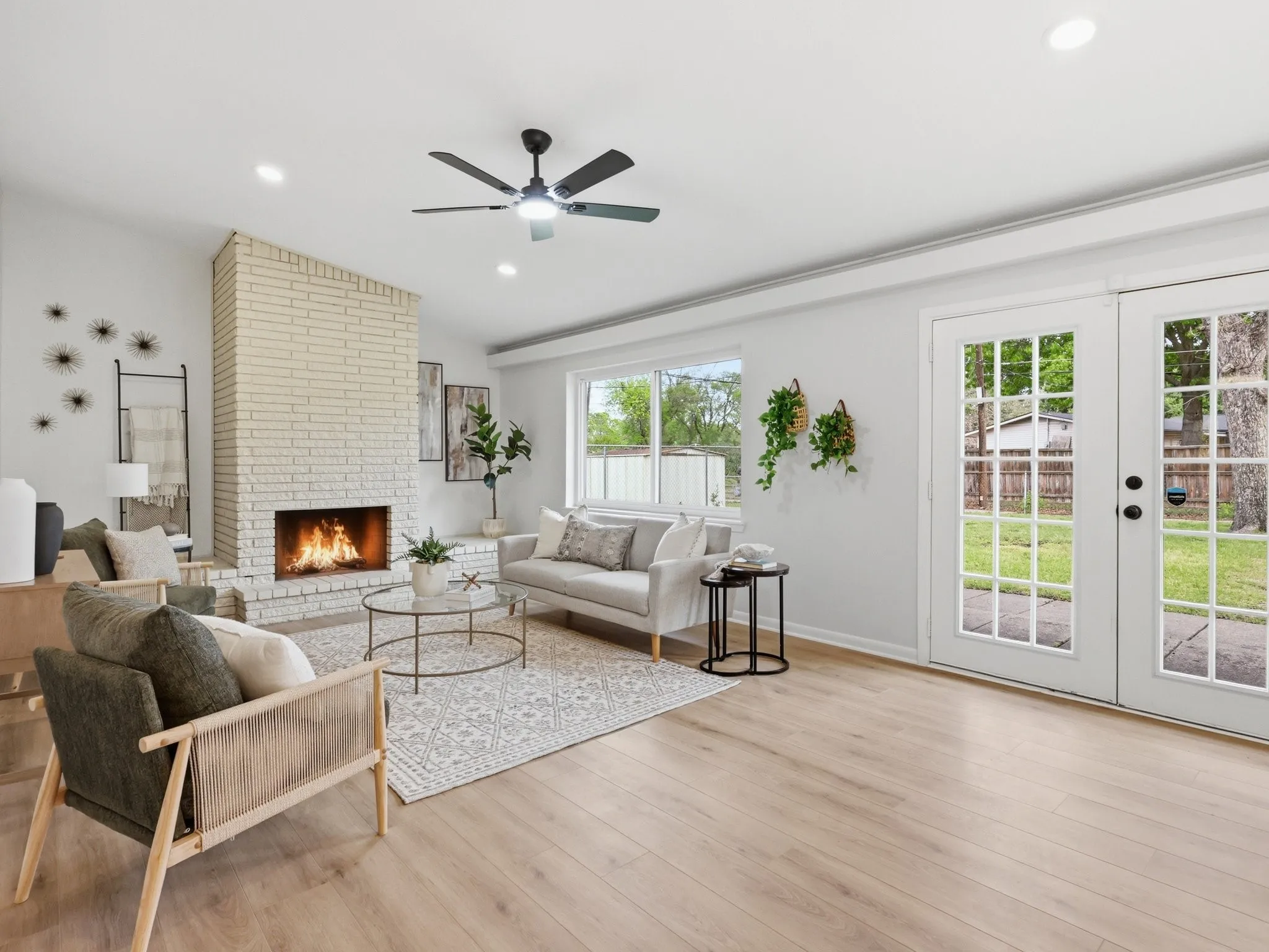 Vaulted ceiling with recessed lighting and ceiling fan, wood-finish flooring, brick fireplace, and double French doors opening to the exterior