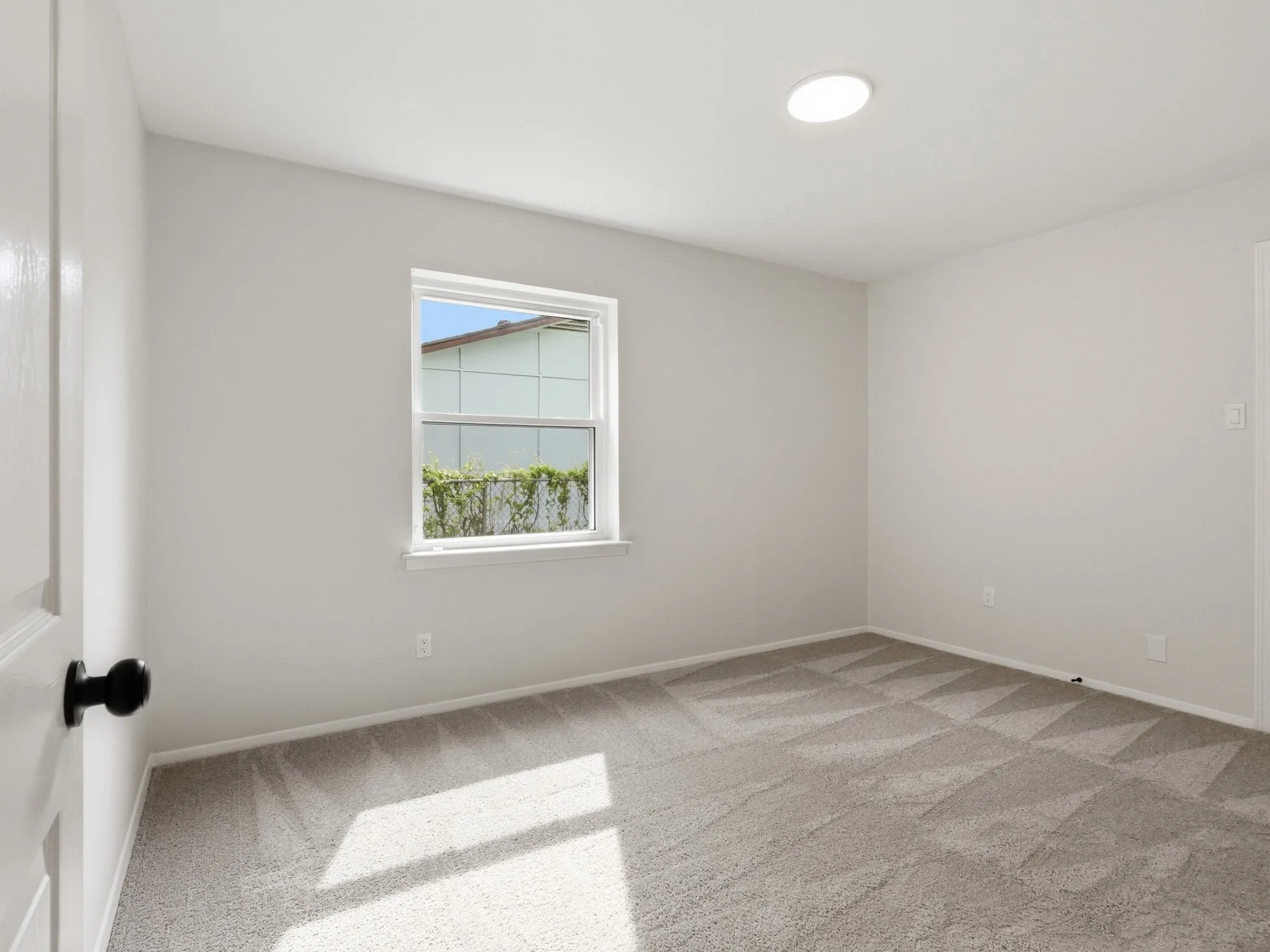 Recessed ceiling lighting, a framed window, light gray wall finish, and patterned carpeting