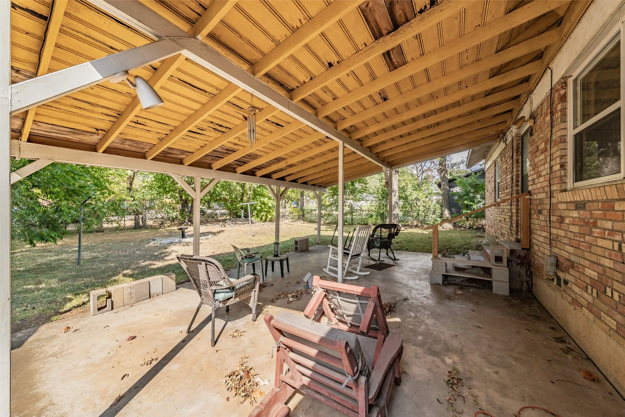 Covered patio with a wood-plank ceiling, concrete flooring, and brick exterior wall