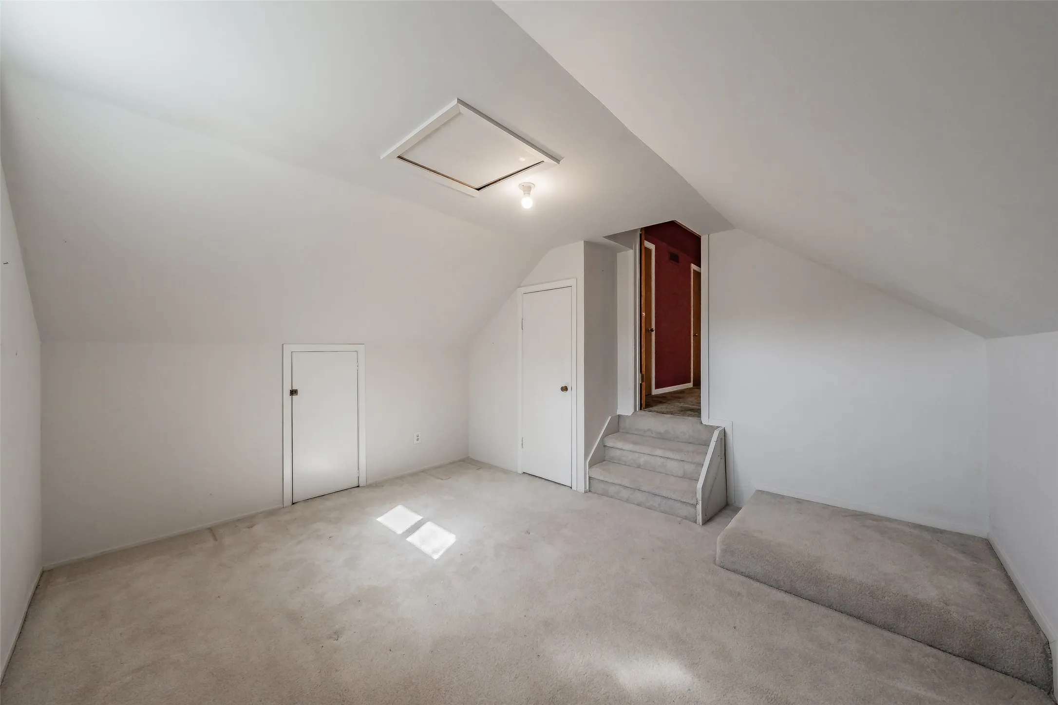 Carpeted flooring, sloped ceiling, recessed storage doors, and a built-in step-up platform