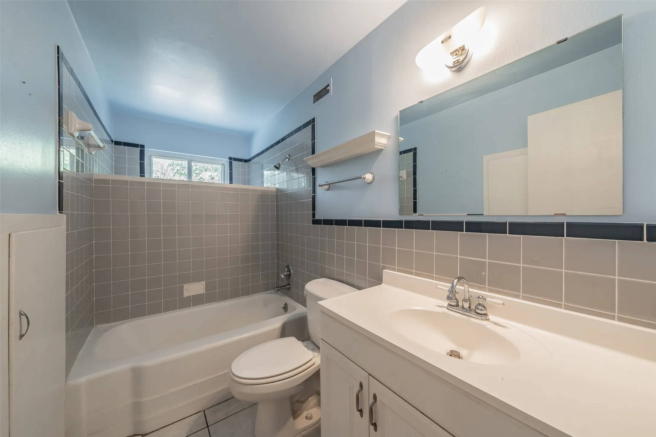 Bathroom featuring a white vanity with integrated sink, chrome faucet, and expansive mirror