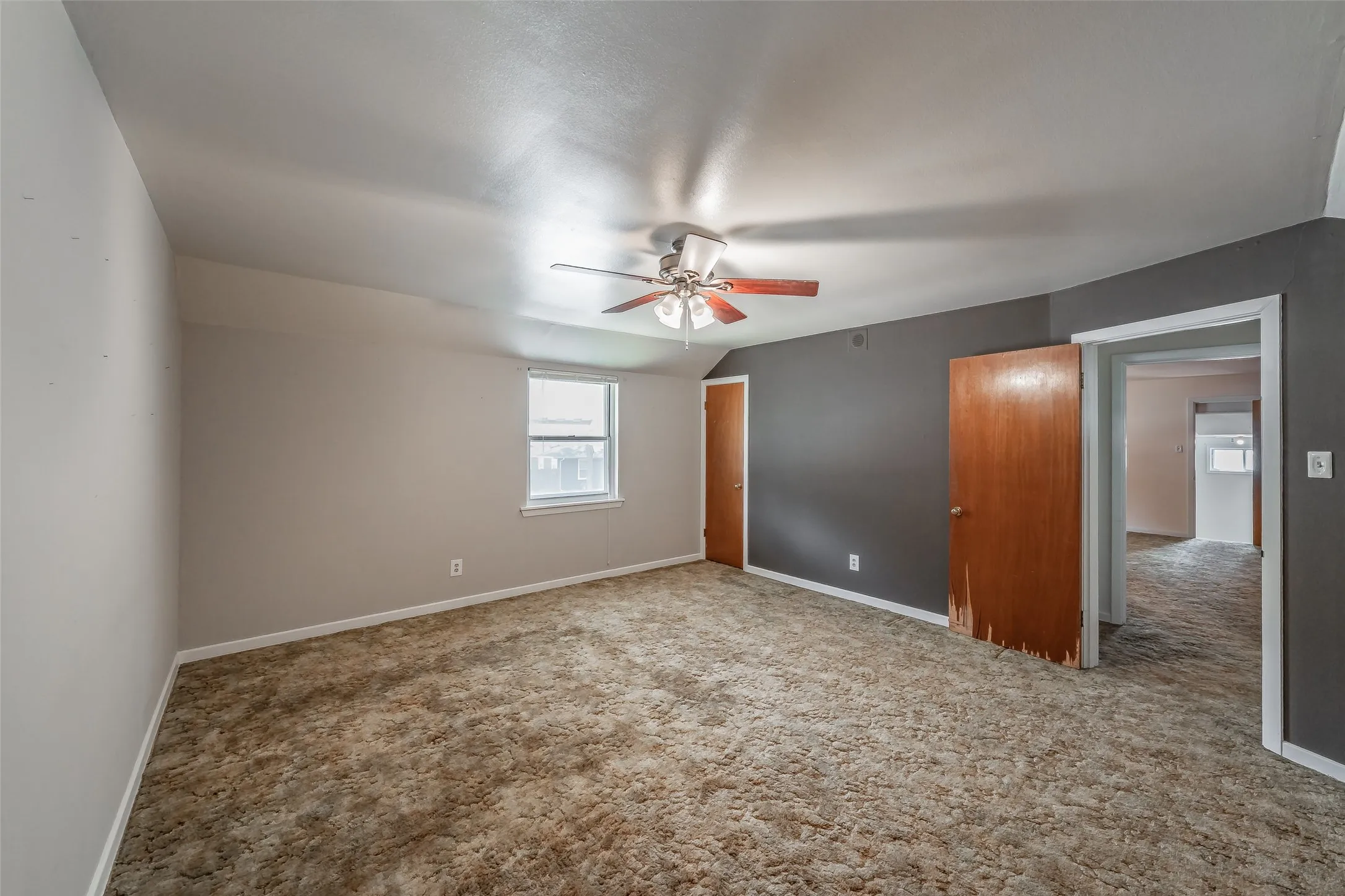 Carpeted flooring, ceiling fan with light fixture, window with white trim, wood-finish doors, and painted walls