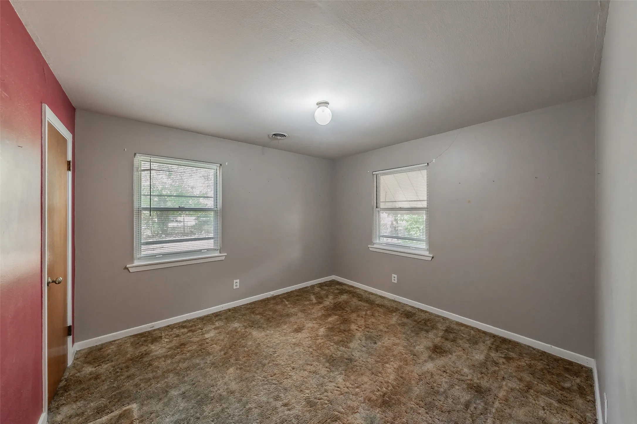 Room featuring two windows, neutral-toned walls, and a ceiling-mounted light fixture
