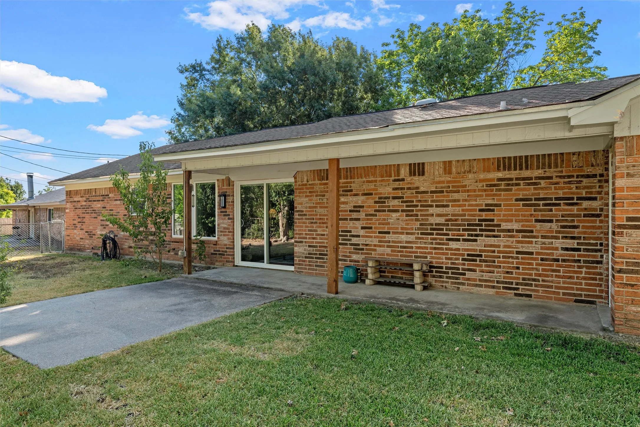 Brick exterior with a covered patio, wood support posts, and sliding glass doors