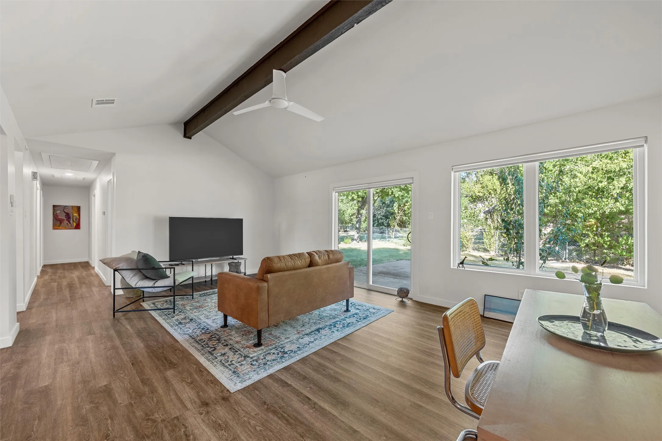 Vaulted ceiling with an exposed beam, wood-finish flooring, recessed lighting, ceiling fan, and sliding glass door