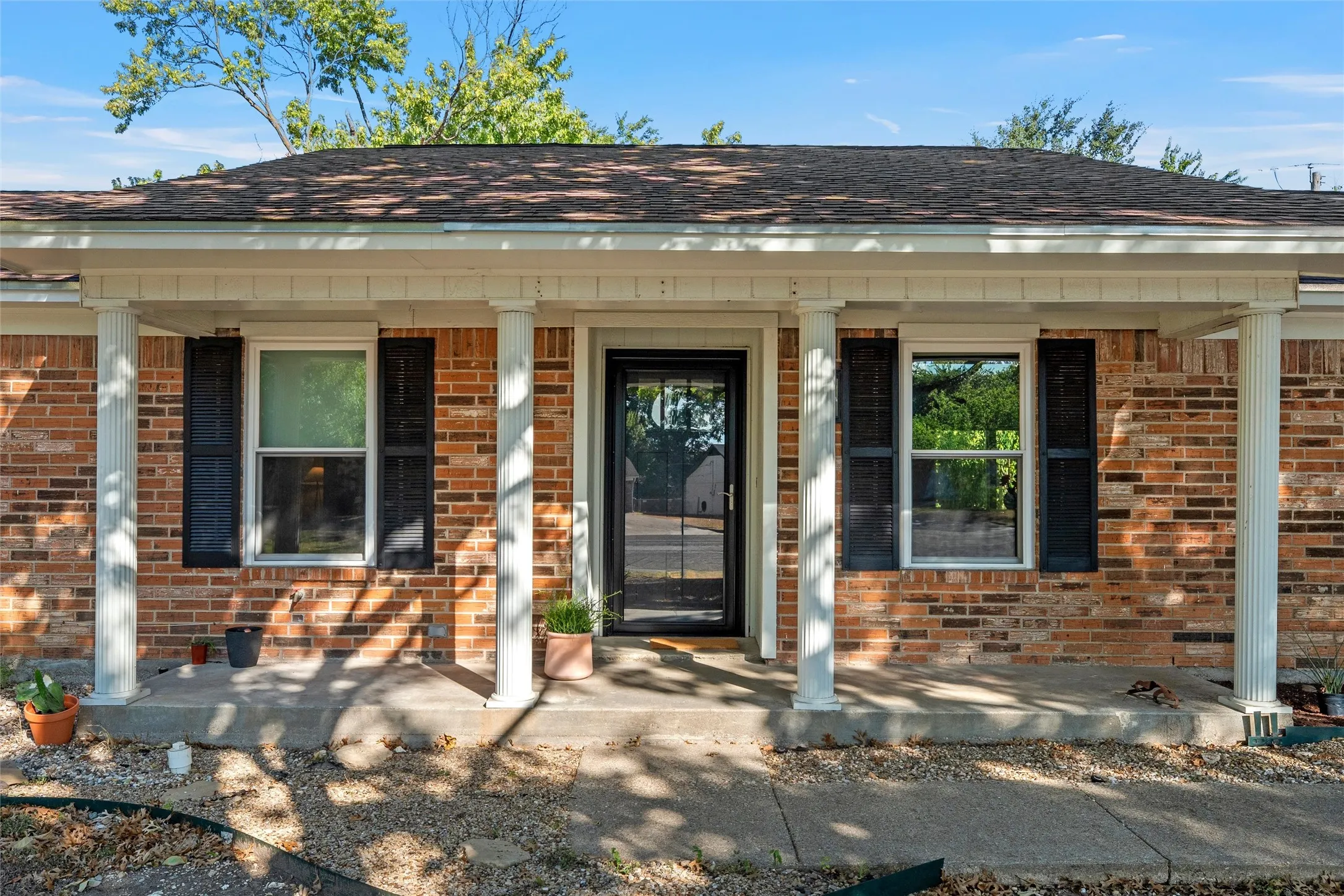 Brick facade with white columned porch and dark shutters