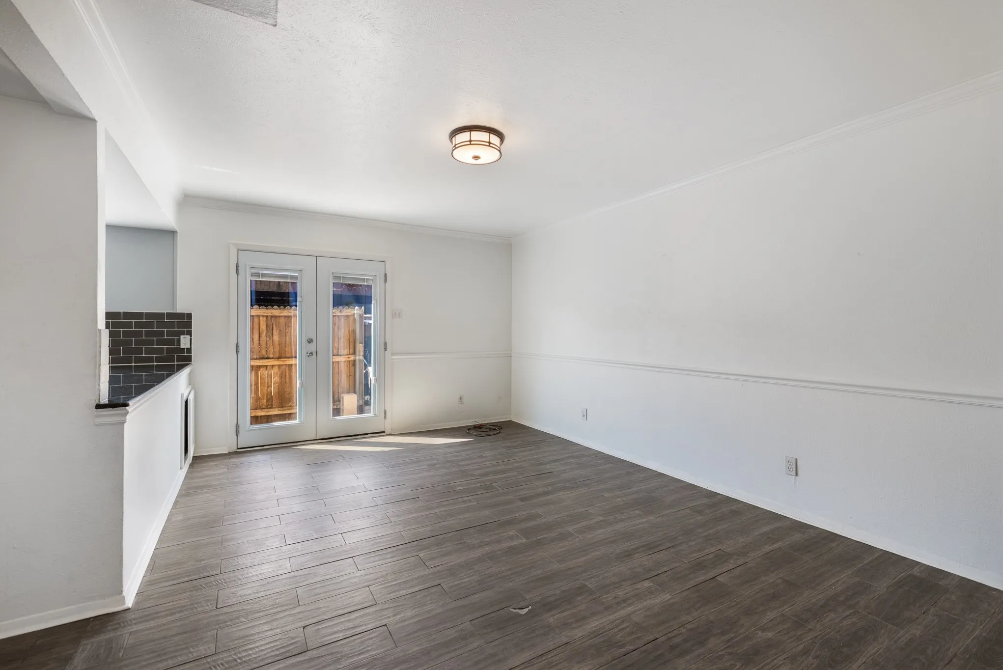 Wood-finish flooring, white walls with chair rail molding, and a flush-mount ceiling light