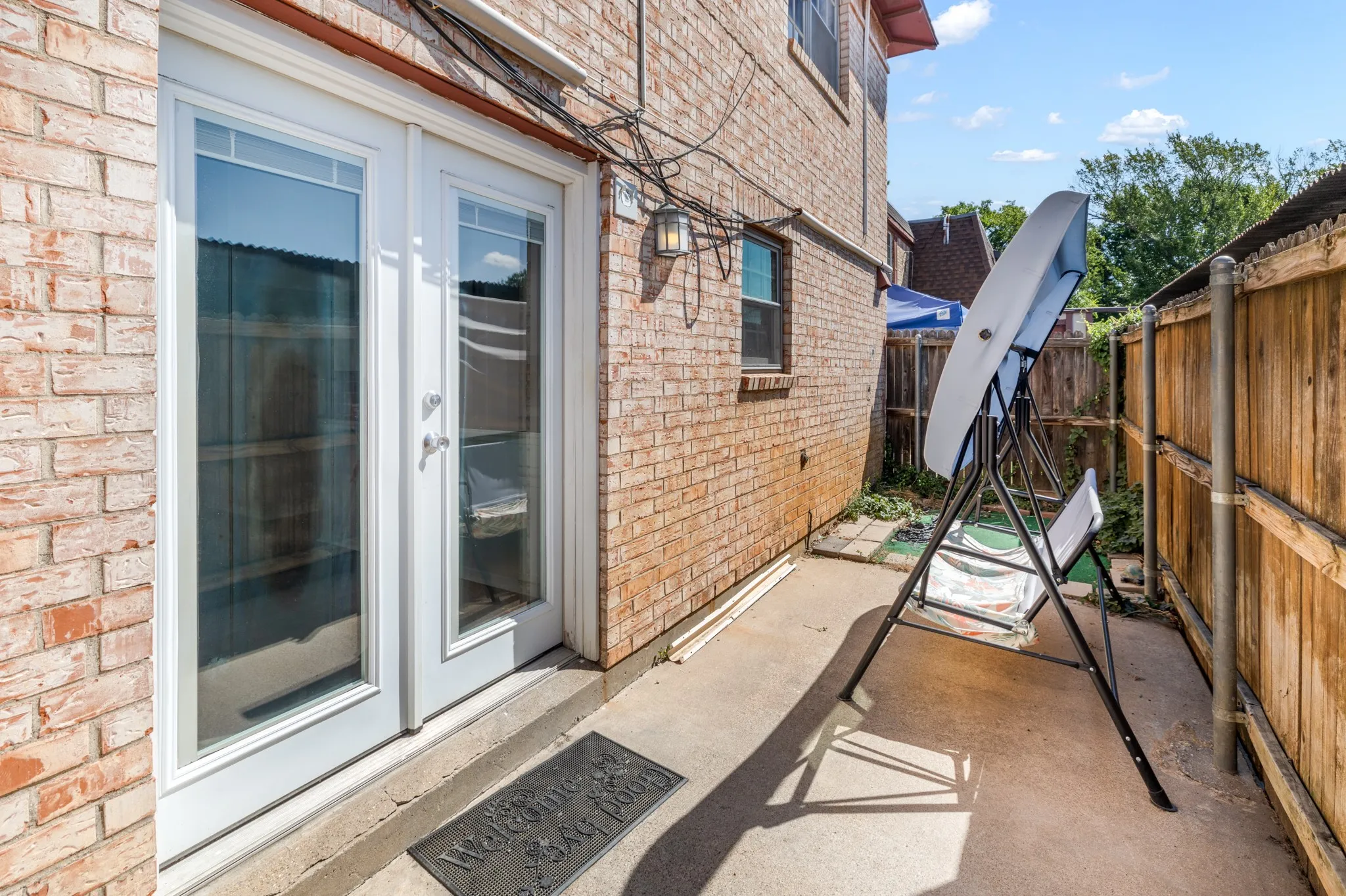 Brick exterior with white double-pane French doors and an exterior wall lantern