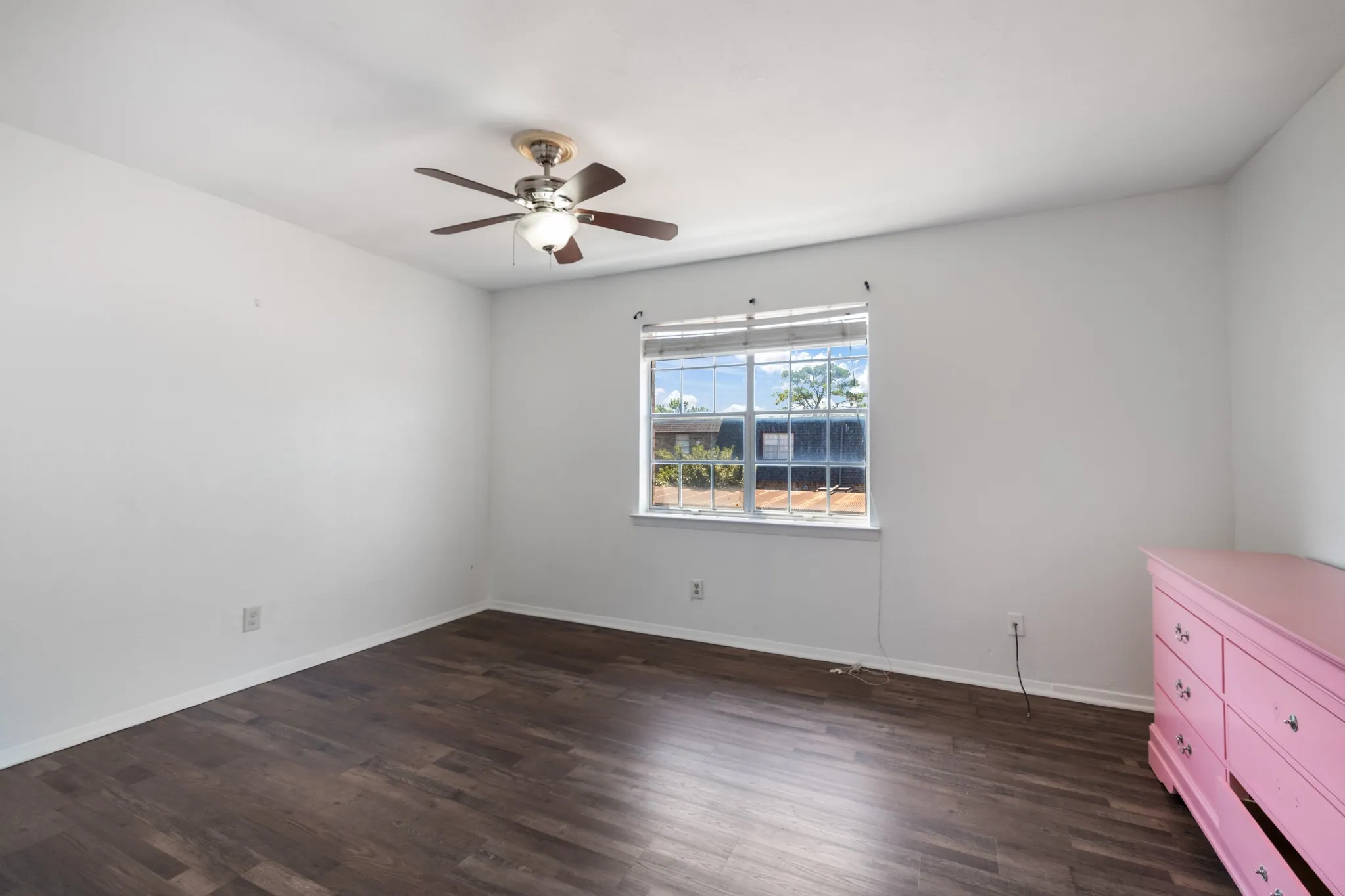 Wood-finish flooring, white walls, ceiling fan with integrated lighting, and a single window with blinds