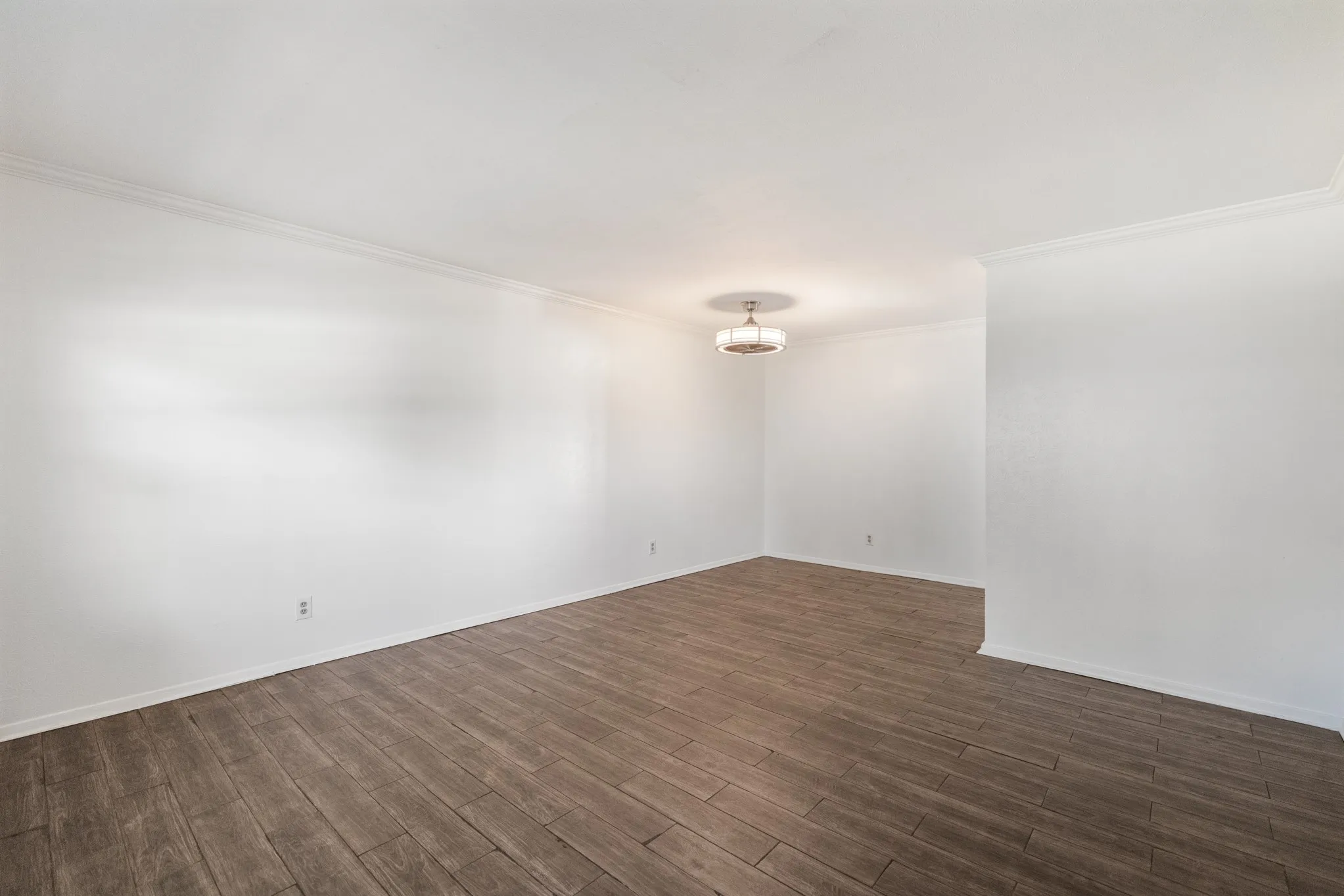 Wood-finish flooring, white walls, crown molding, and a drum-style ceiling light fixture