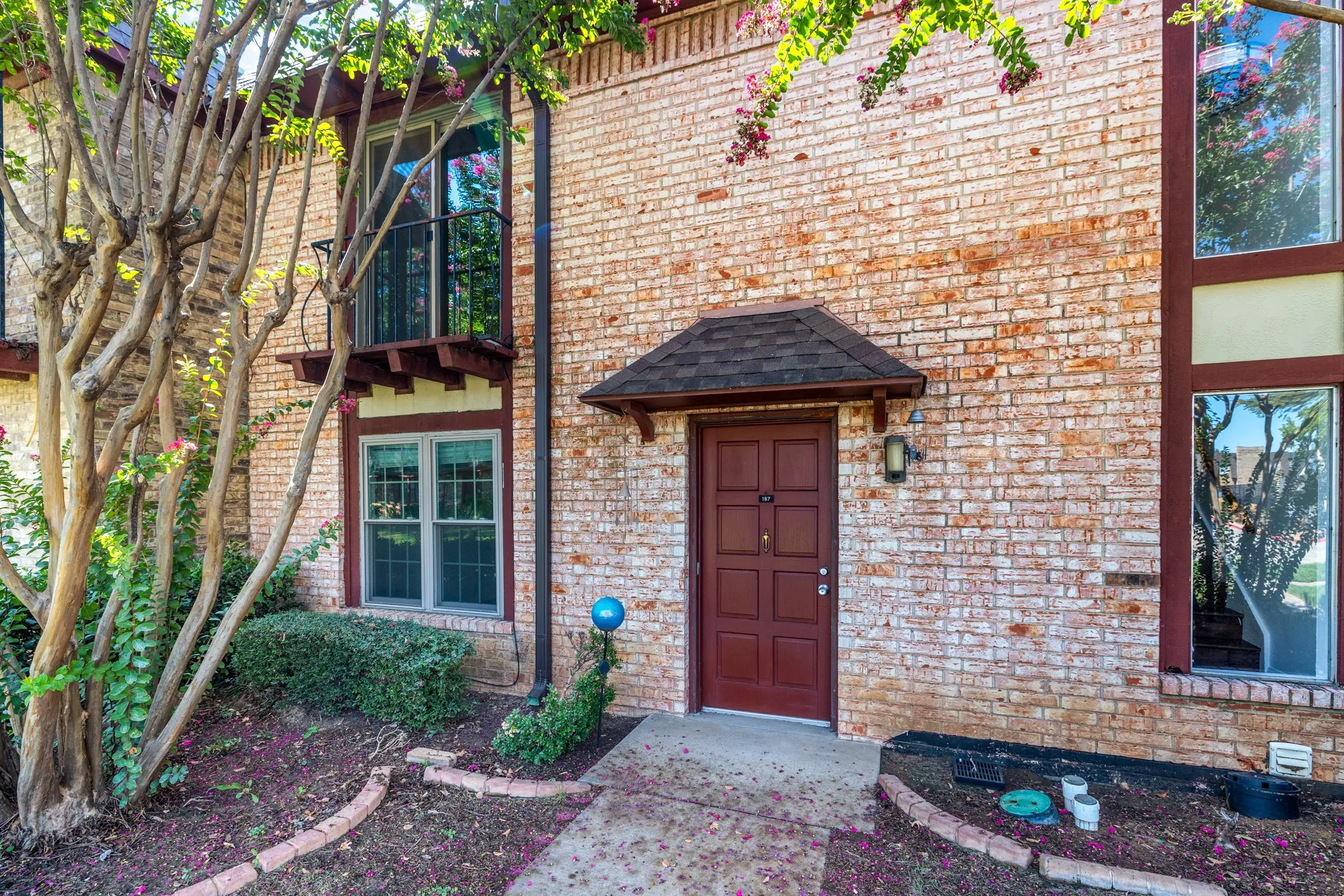 Brick exterior featuring a covered entry, transom window, recessed window, and second-story balcony with metal railing