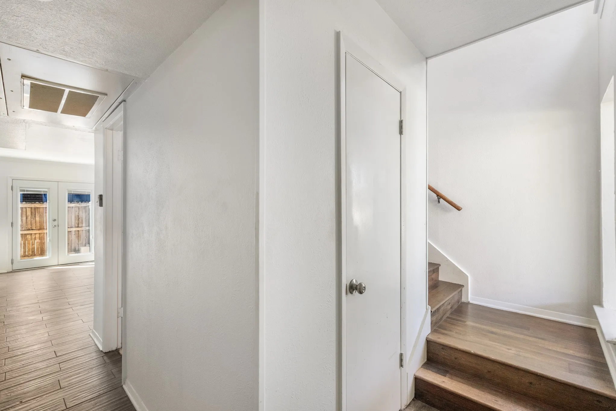 Wood-finish flooring, white paneled doors, and a wood handrail
