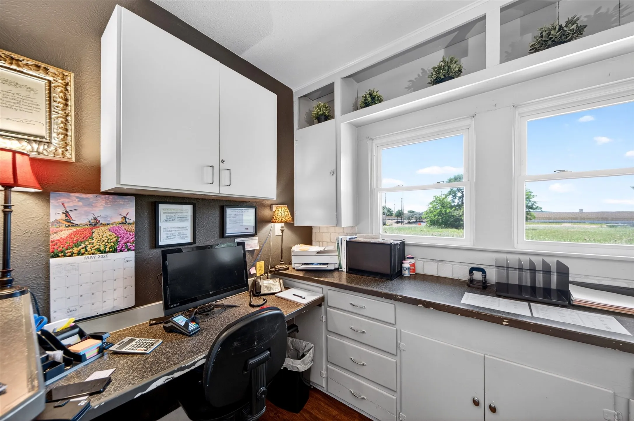 Dedicated workspace featuring built-in cabinetry, dual windows, and ample counter space