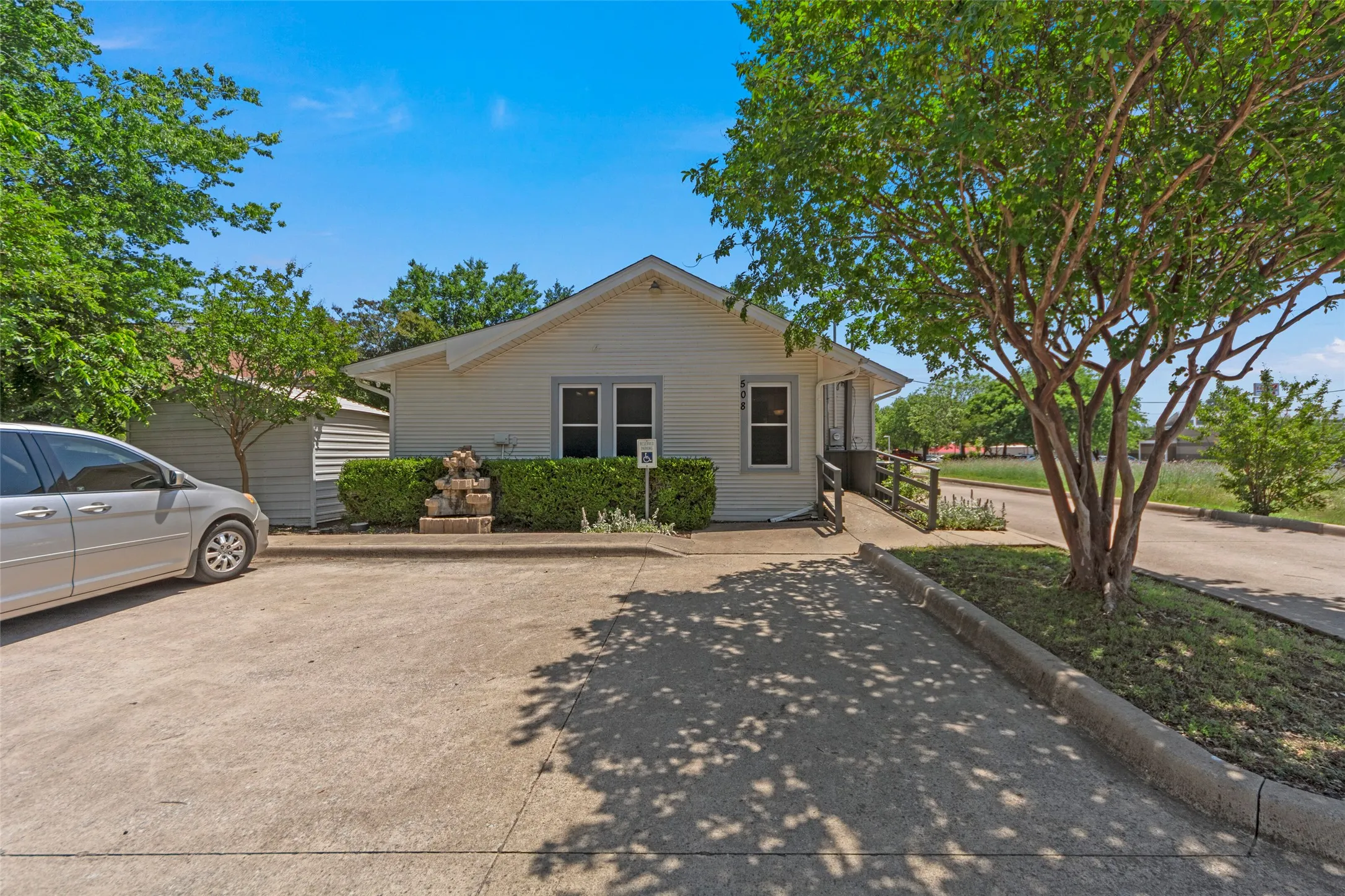 Charming single-story home featuring a gable roof, front-facing windows with dark trim, and a concrete driveway