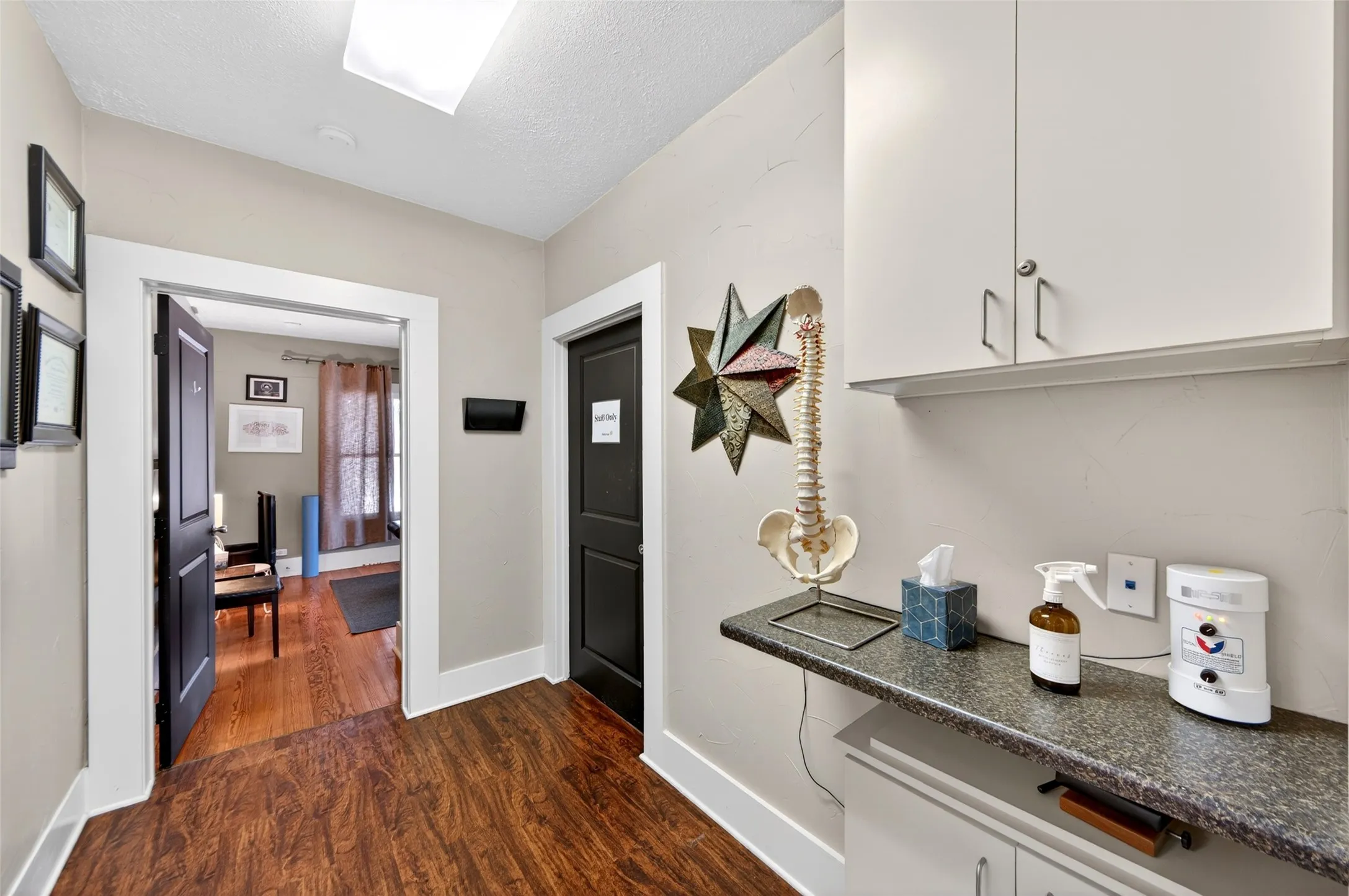 Wood-finish flooring, white trim, recessed lighting, built-in upper cabinetry, and a countertop with lower cabinetry