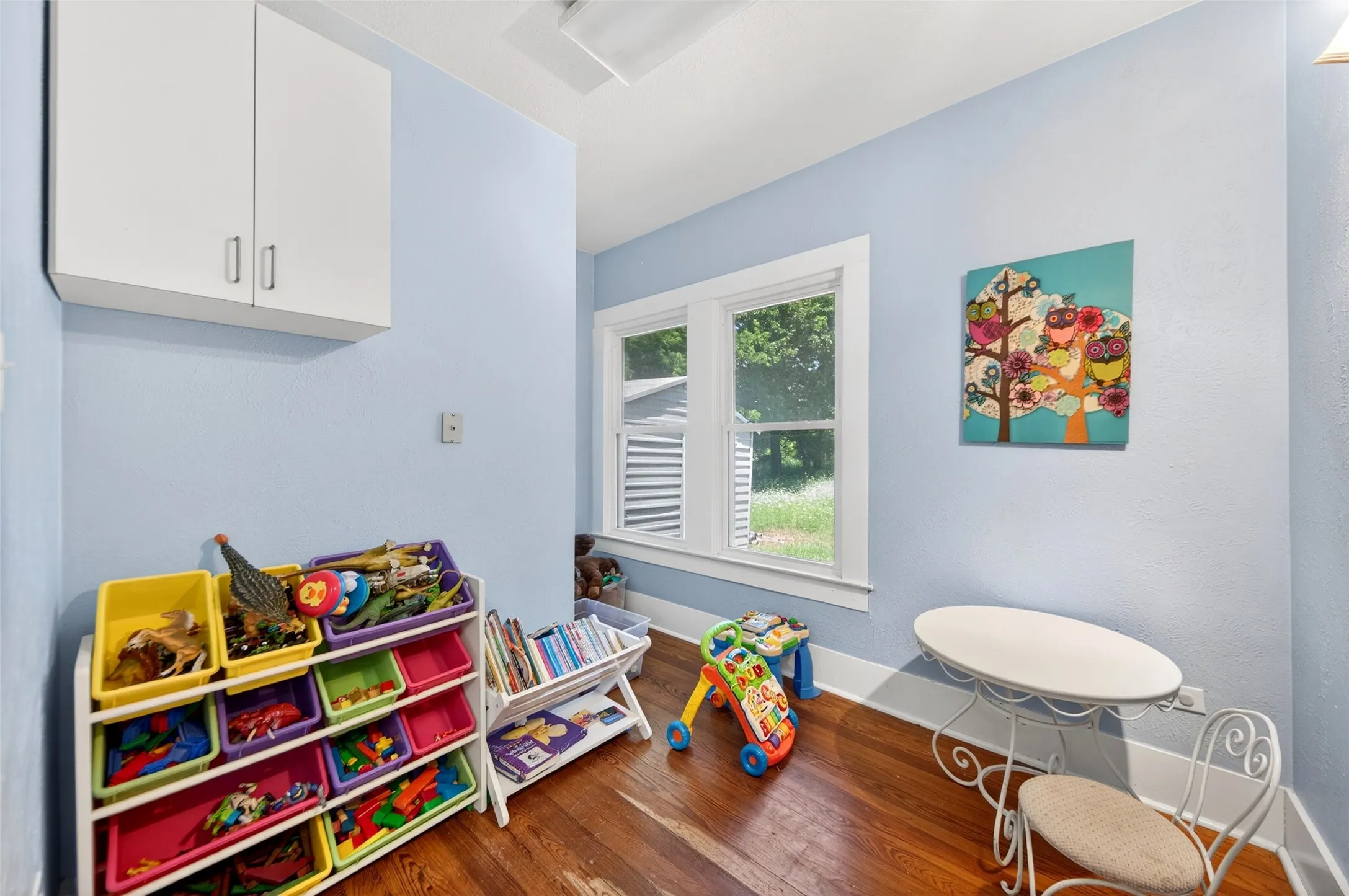 Hardwood flooring, painted walls, white trim, white window frame, and built-in white cabinetry