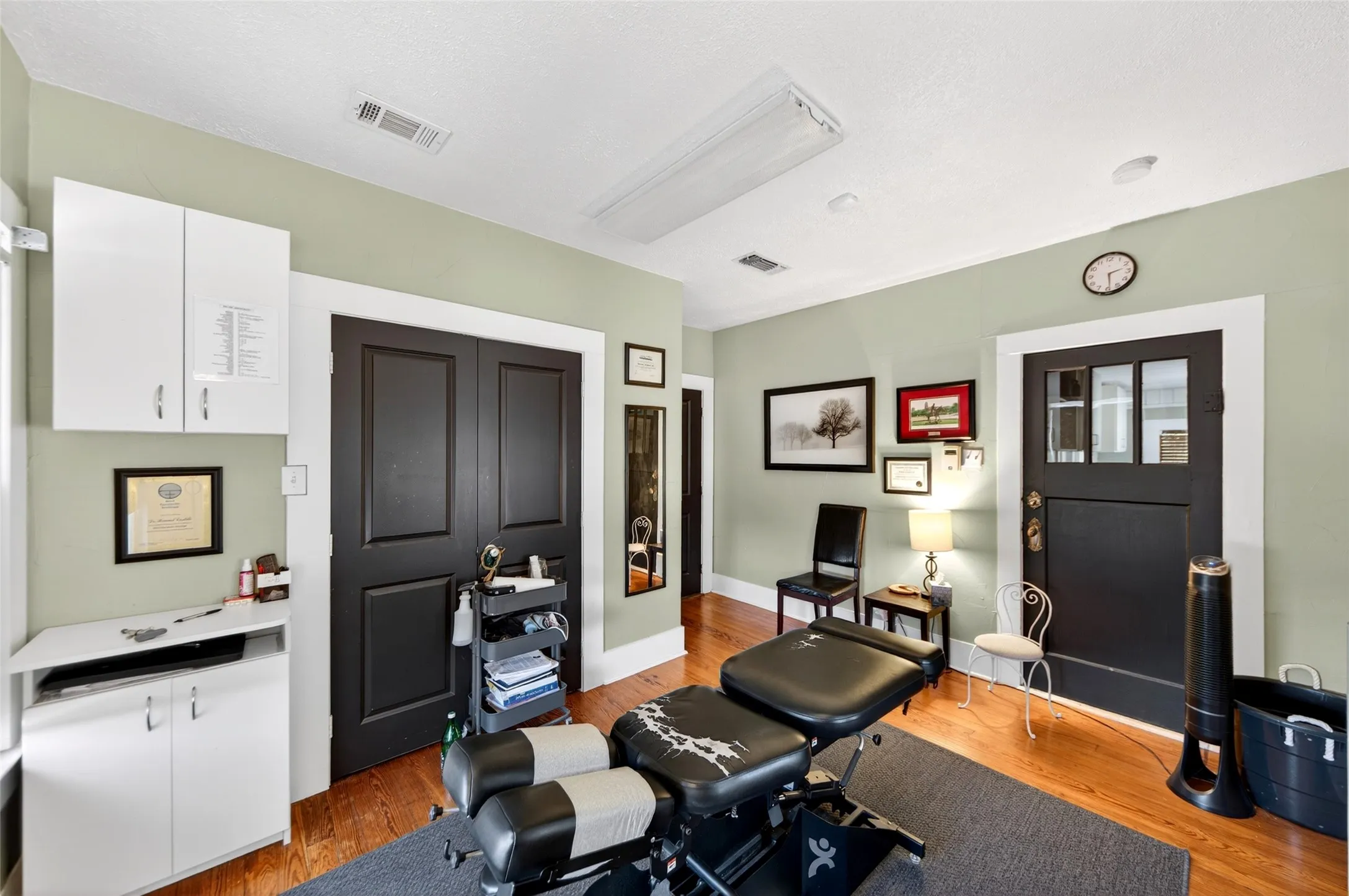 Hardwood-finish flooring, built-in white cabinetry, black paneled doors, and a decorative transom window