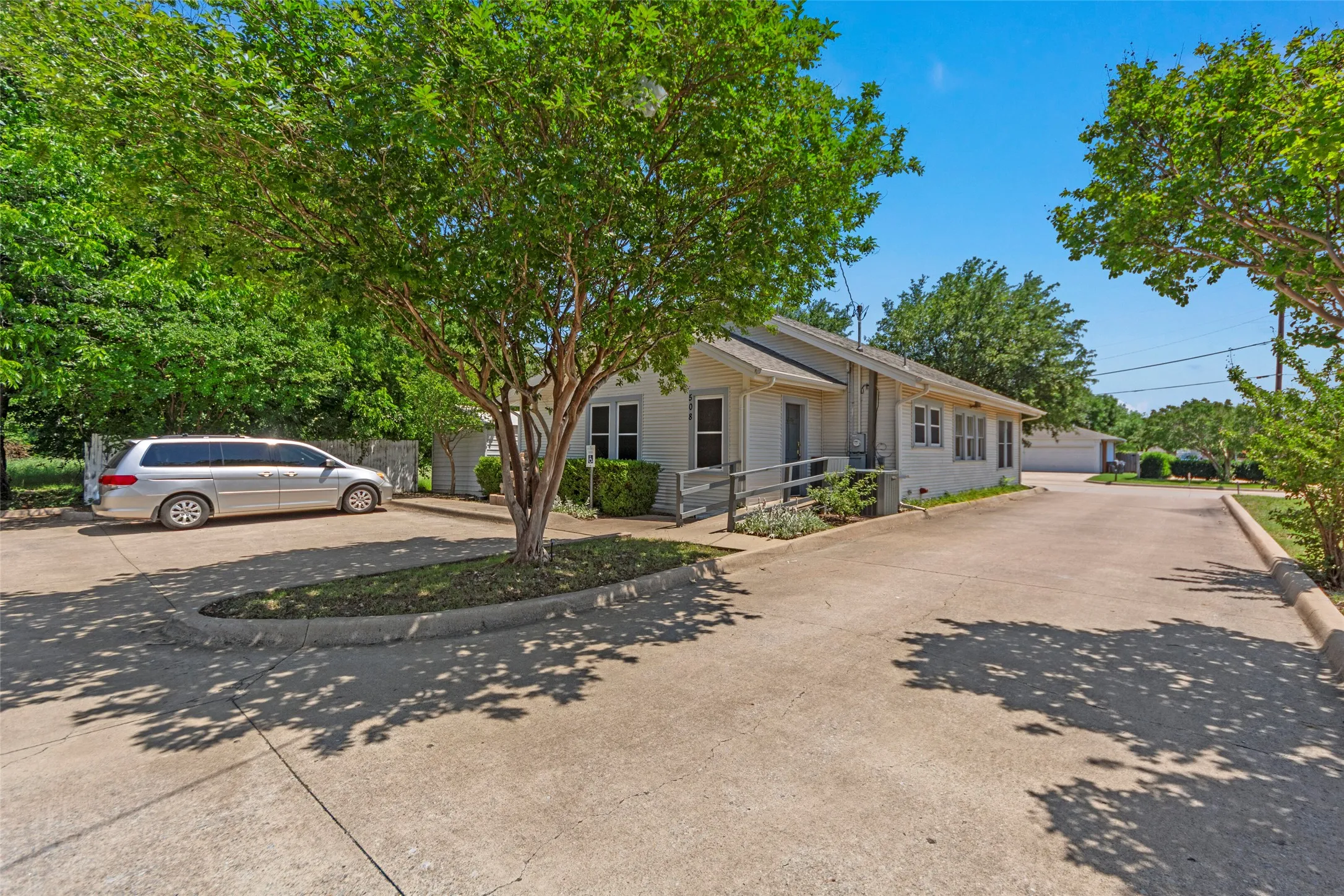 Expansive concrete parking area with mature trees and landscaping