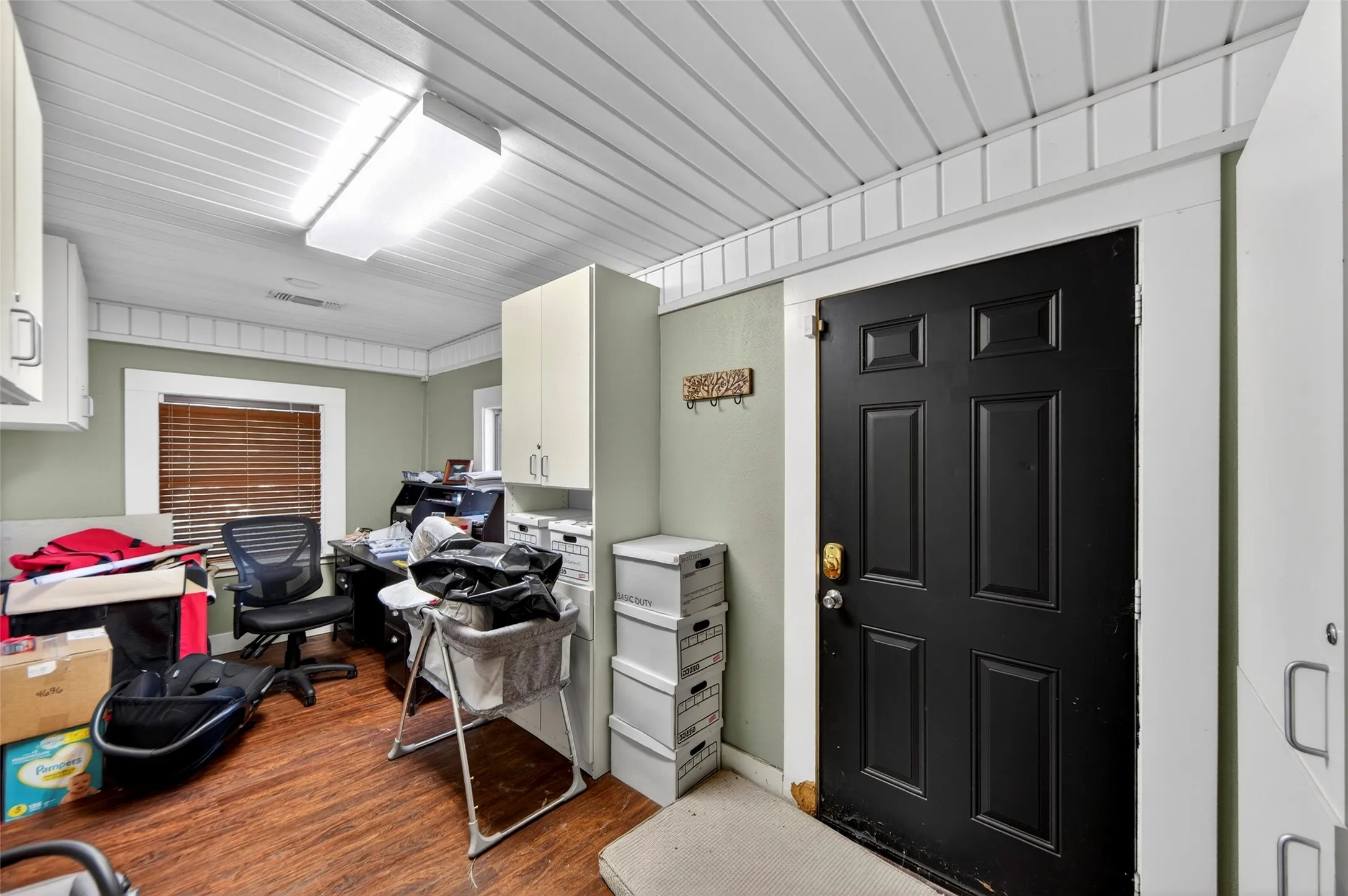 White plank ceiling with decorative trim, wood-finish flooring, and white built-in cabinetry