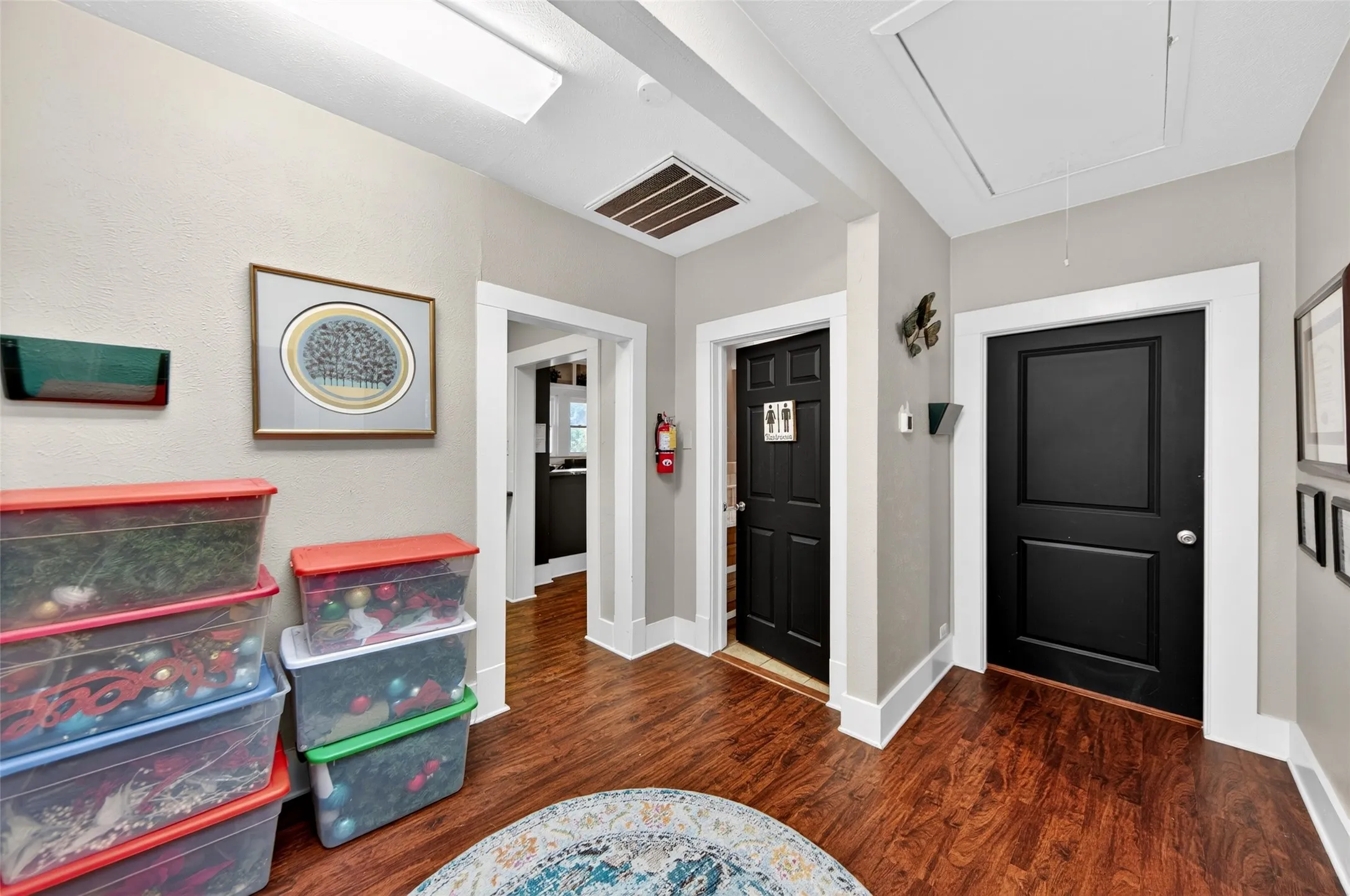 Wood-finish flooring with white trim and dark panel doors