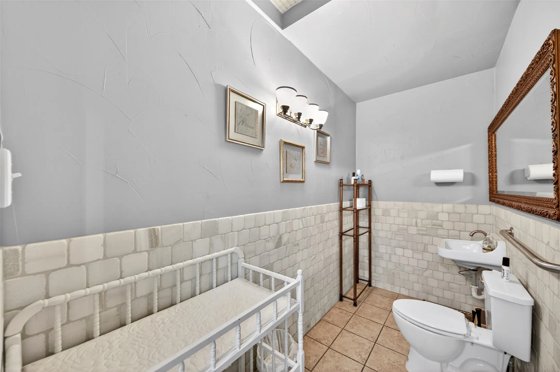 Light gray wall finish with wainscoting, pedestal sink, and tiled flooring