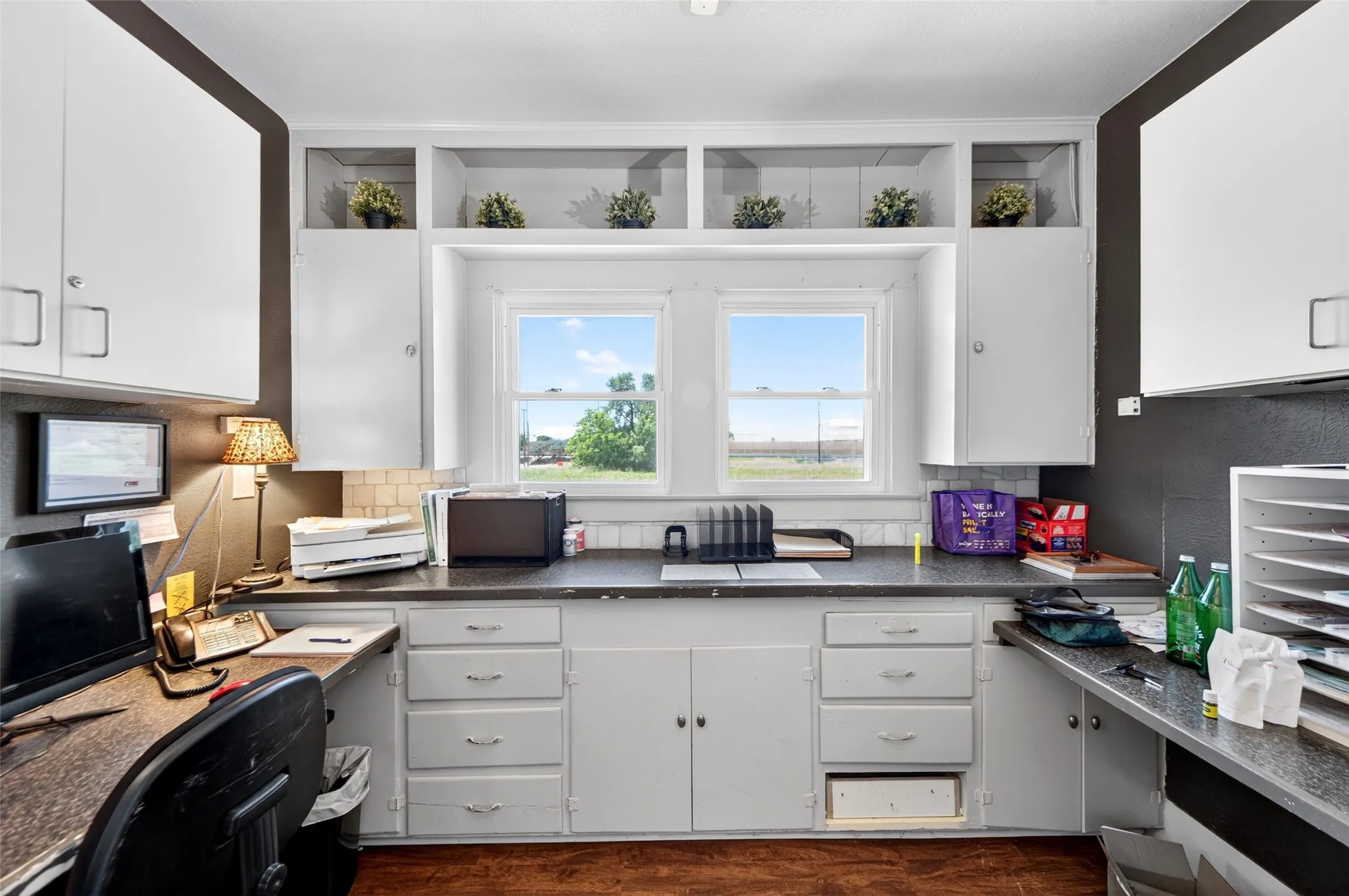 Built-in white cabinetry and shelving, dual windows providing natural light, extensive countertop space, and wood-finish flooring