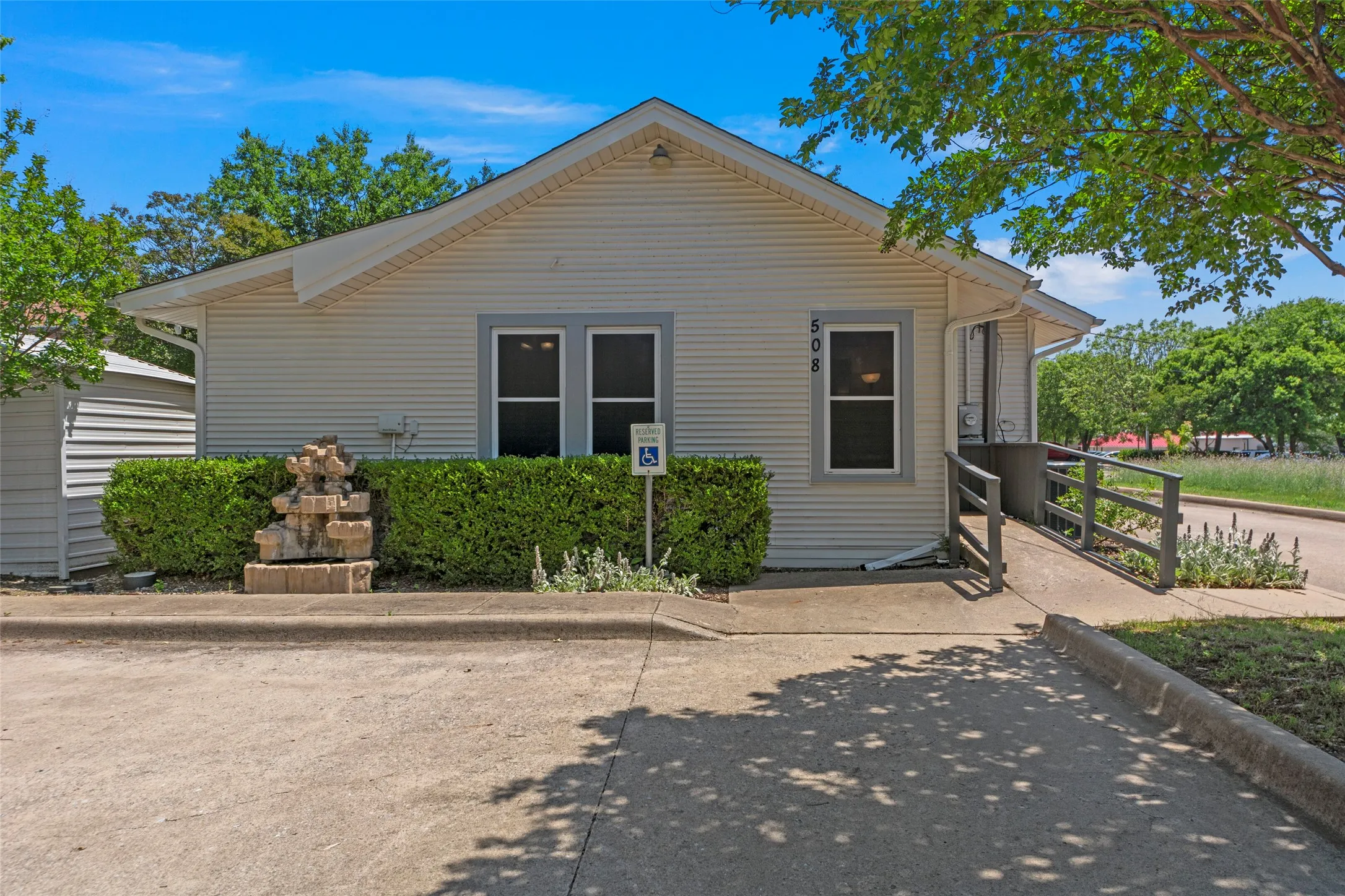 Exterior featuring siding, multiple windows, a tiered fountain, and a ramp access