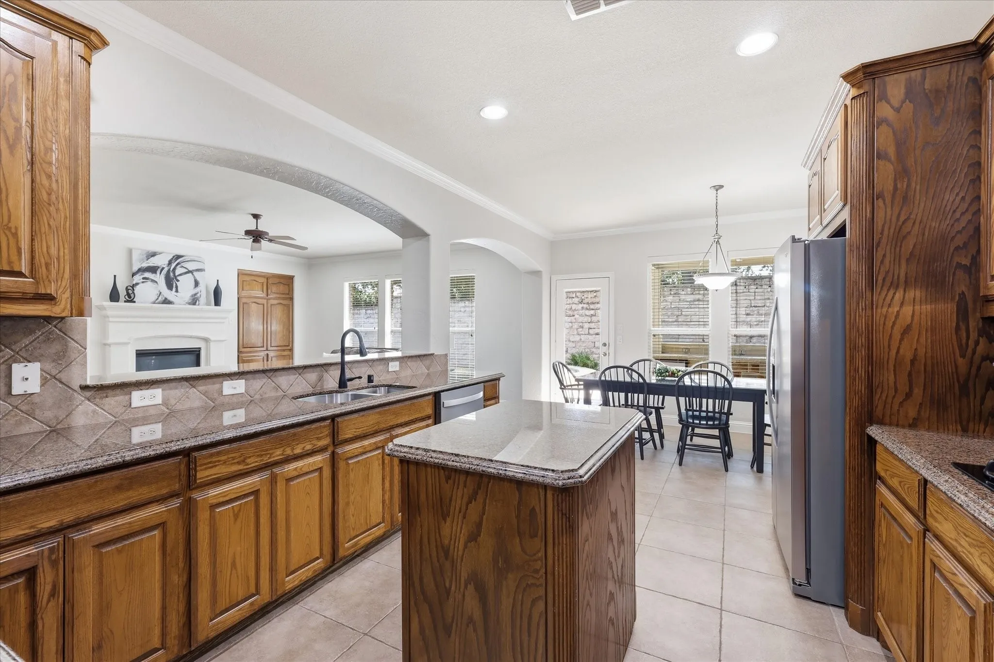 Kitchen featuring wood cabinetry, solid surface countertops, tile flooring, and a center island
