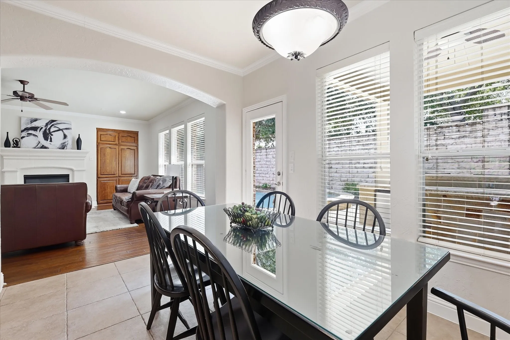 Arched entryway opens to a living area featuring a fireplace with a white mantel and a ceiling fan