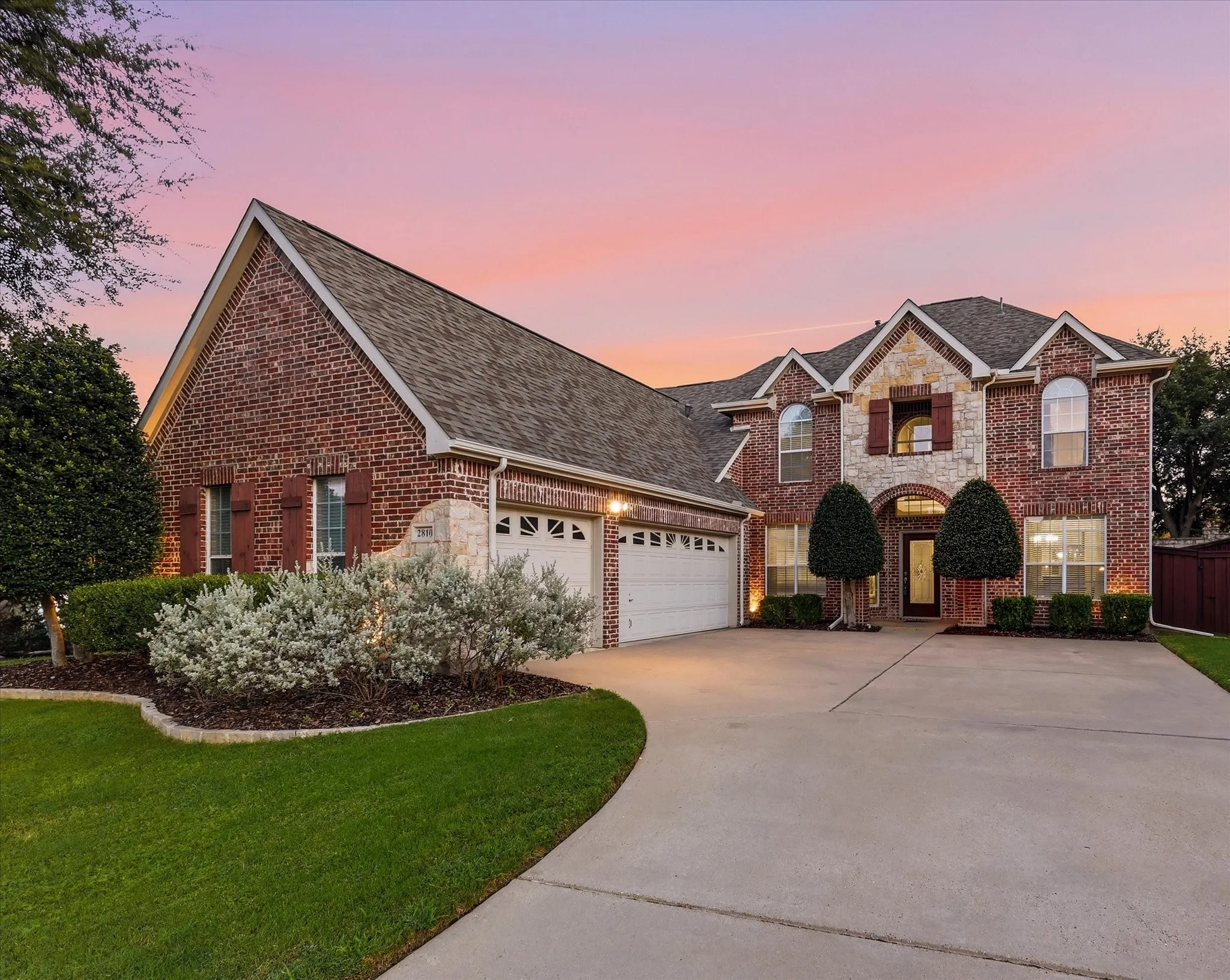 Brick and stone exterior with arched entry, gabled roof, and attached two-car garage