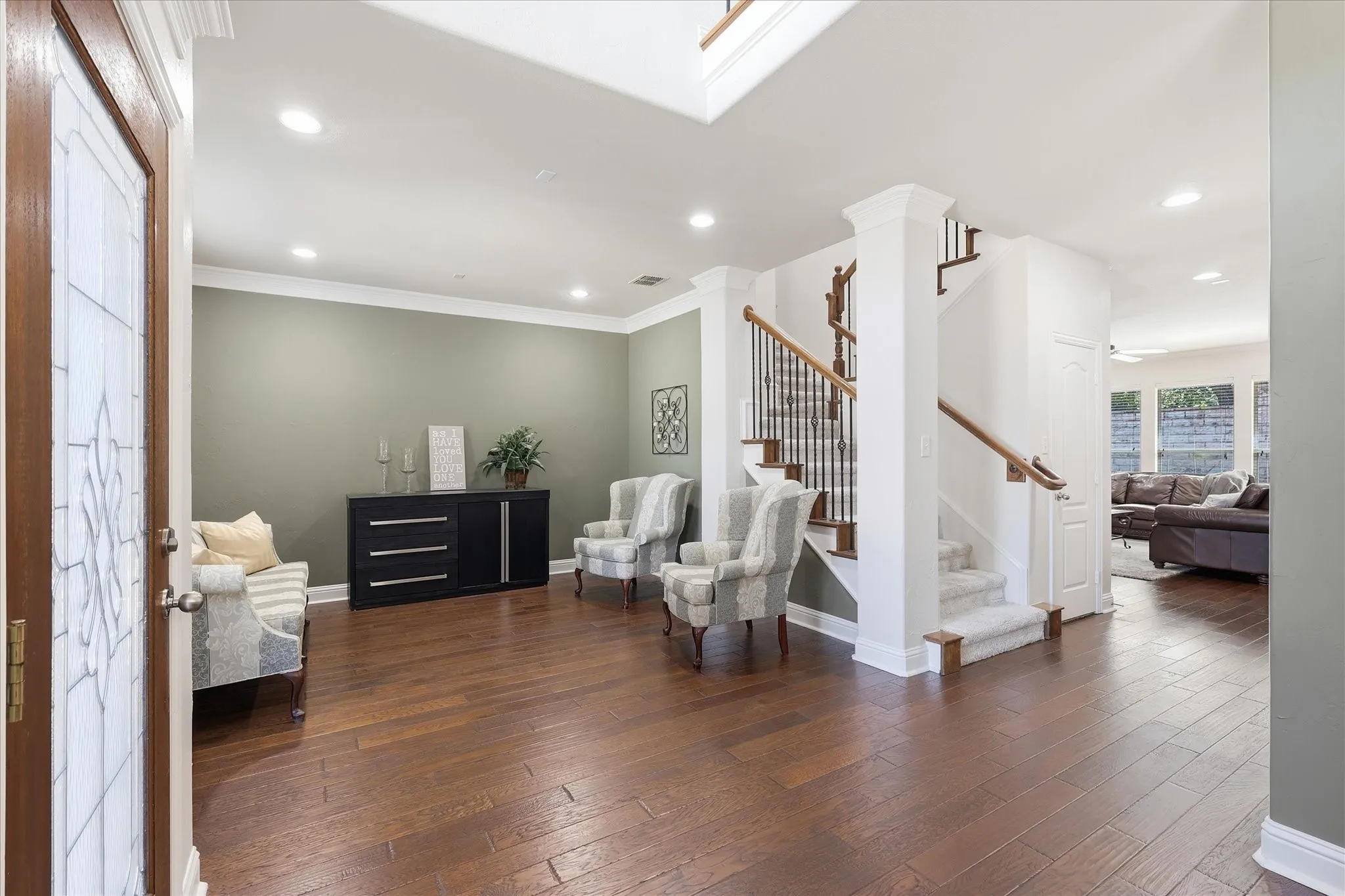 Hardwood flooring, crown molding, recessed lighting, and a carpeted staircase with wood and wrought iron railing