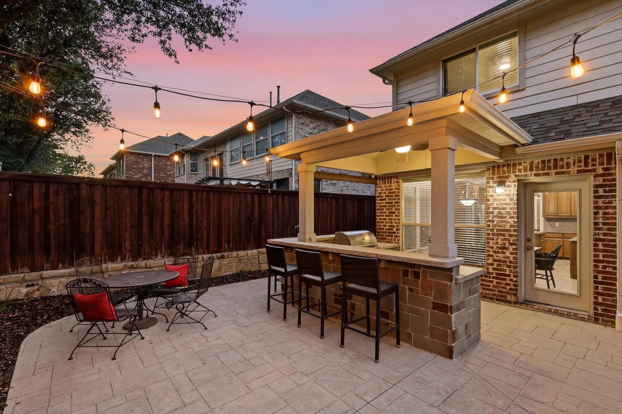 Stamped concrete patio featuring an outdoor kitchen with integrated grill, stone-clad base, and covered bar seating