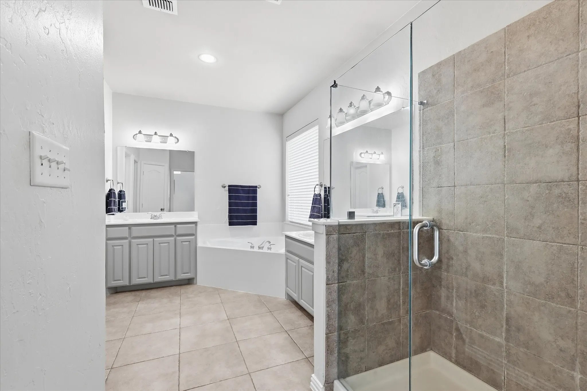 Dual vanity with gray cabinetry, white countertops, and individual mirrors