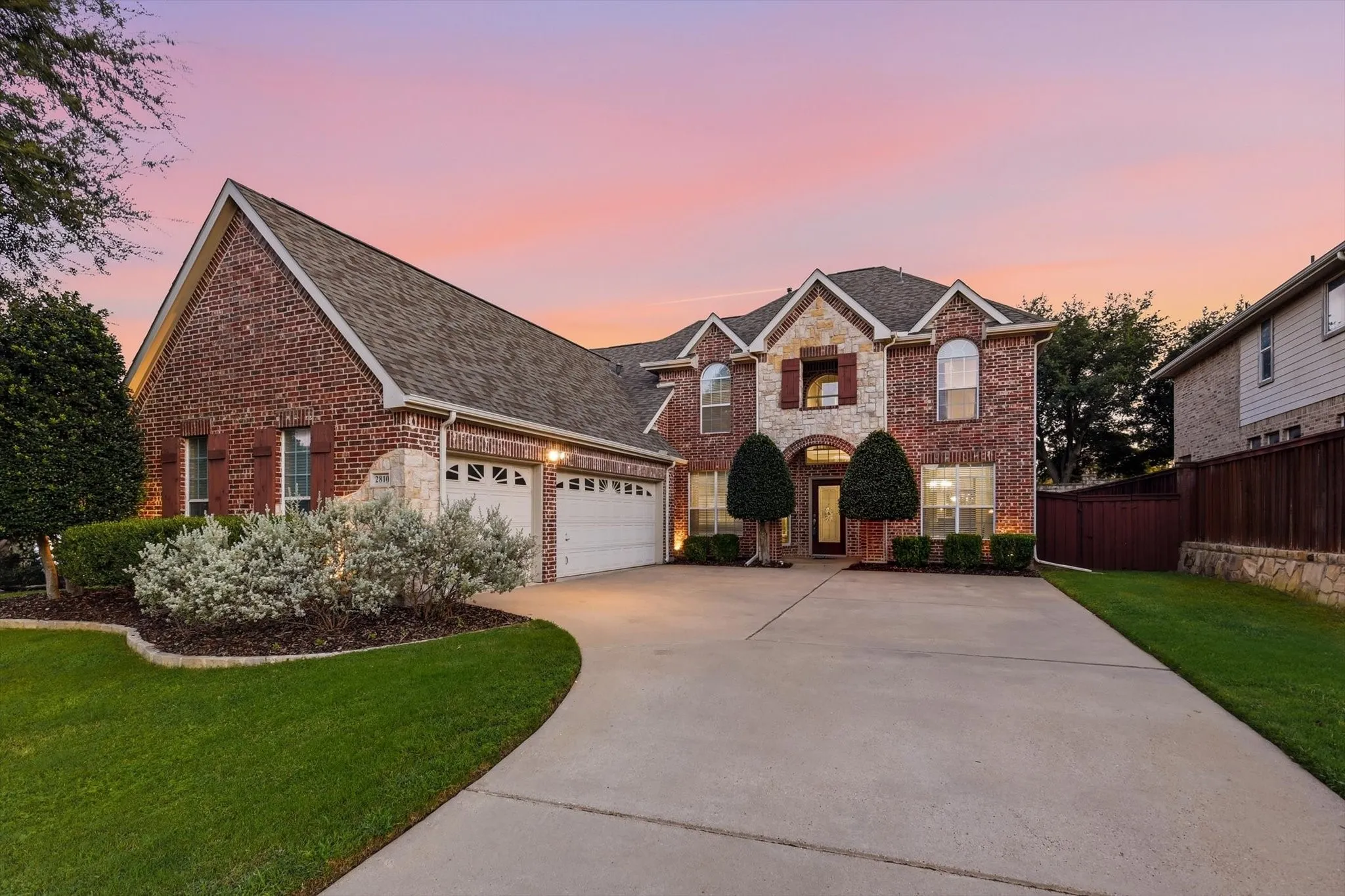 Brick and stone exterior with arched windows, a multi-car garage, and a concrete driveway