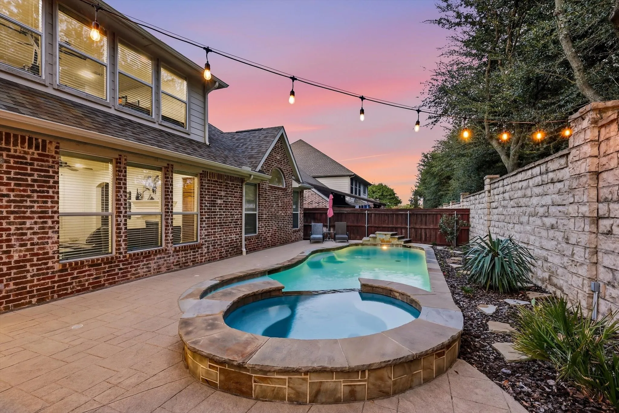 Stamped concrete patio featuring a built-in swimming pool and integrated spa