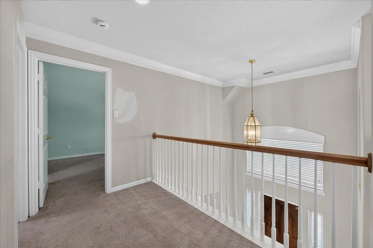 Carpeted hallway with a white baluster and wood-finish handrail