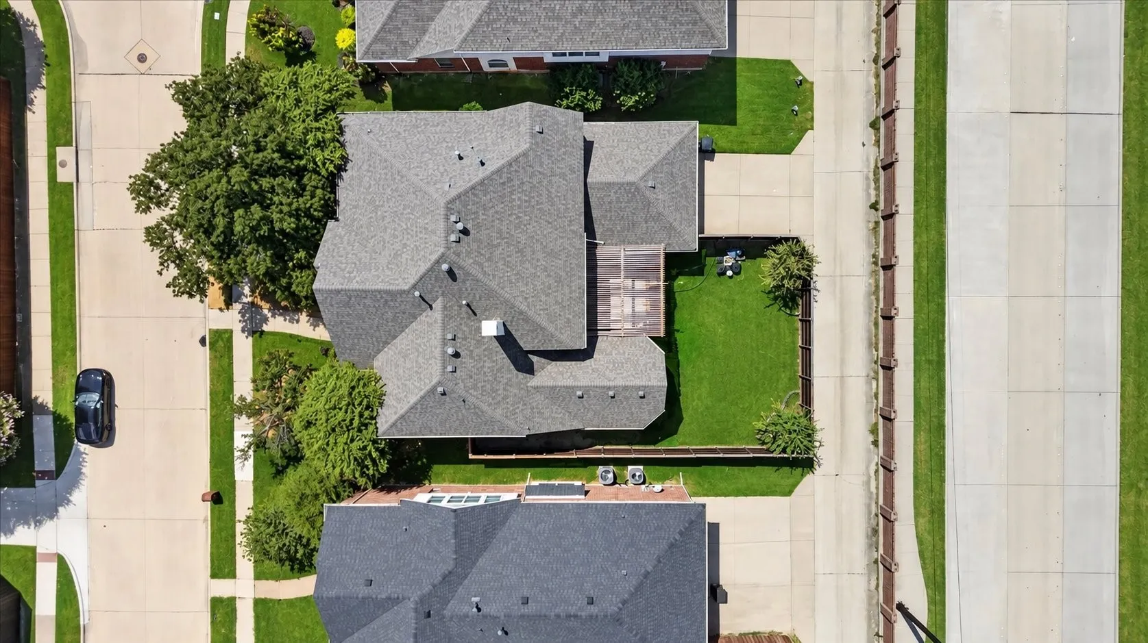 Residential property featuring a shingle roof, well-maintained lawns, and concrete driveways