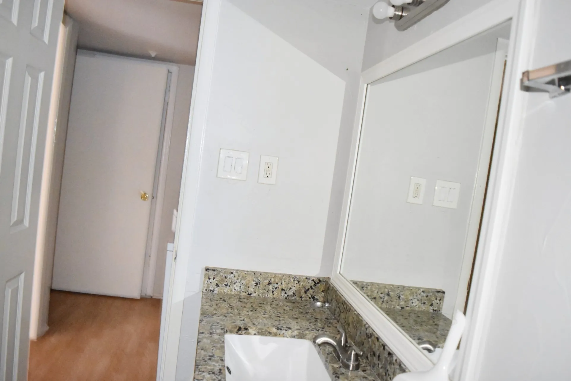 White vanity with a granite-style countertop, undermount sink, and polished chrome faucet