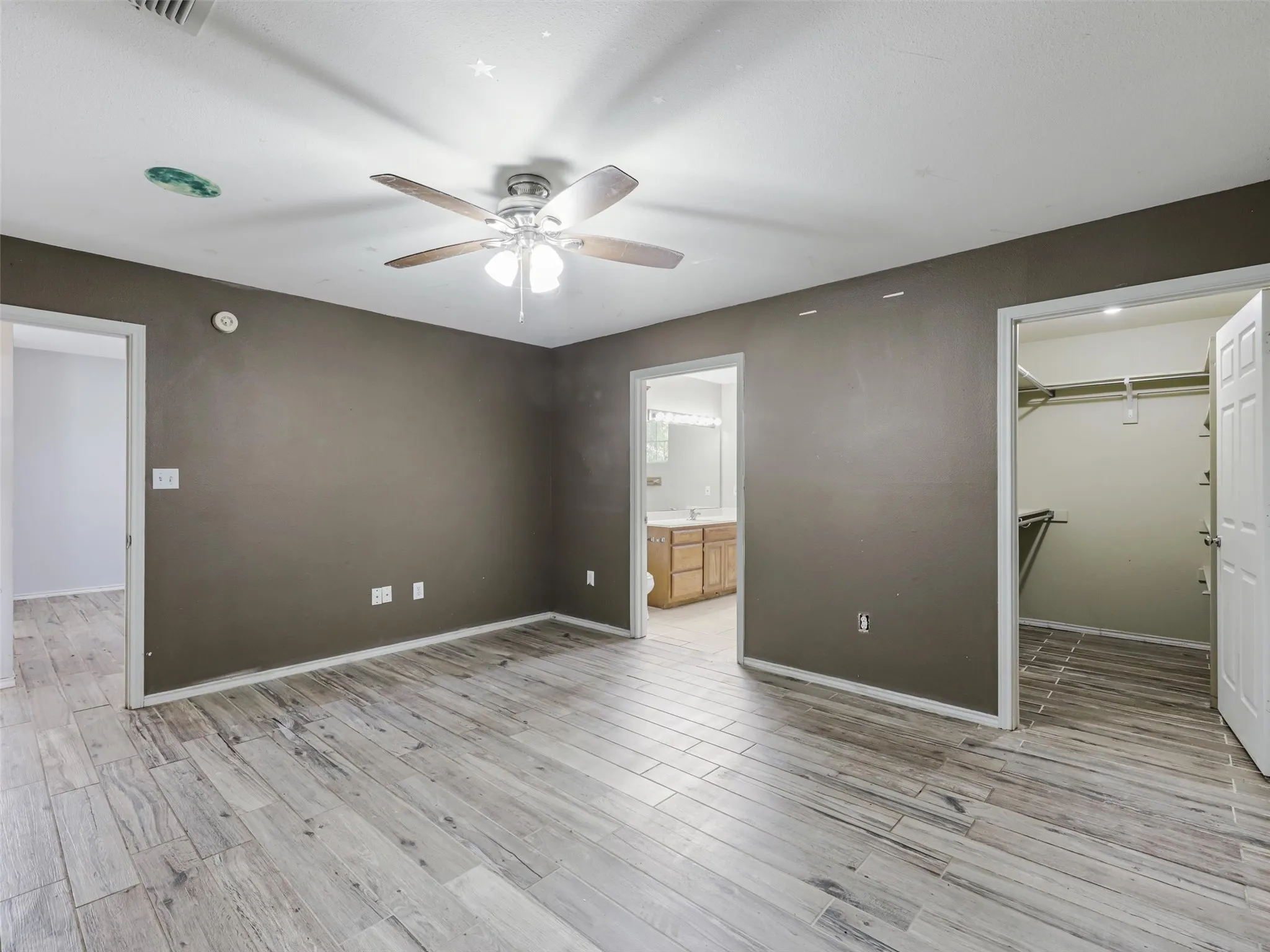 Wood-finish flooring throughout, ceiling fan with integrated lighting, and a walk-in closet with built-in shelving