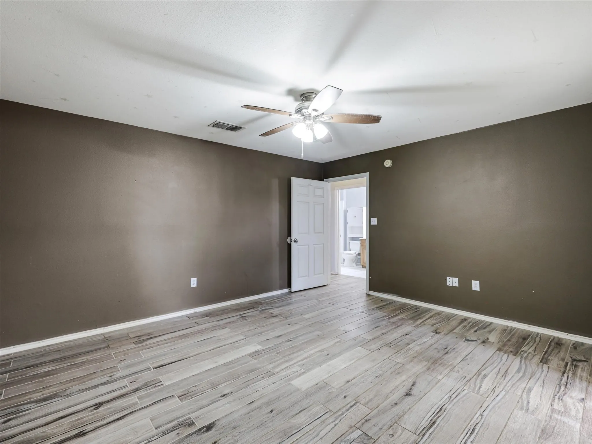 Wood-finish tile flooring throughout, dark accent wall, and a ceiling fan with light fixture