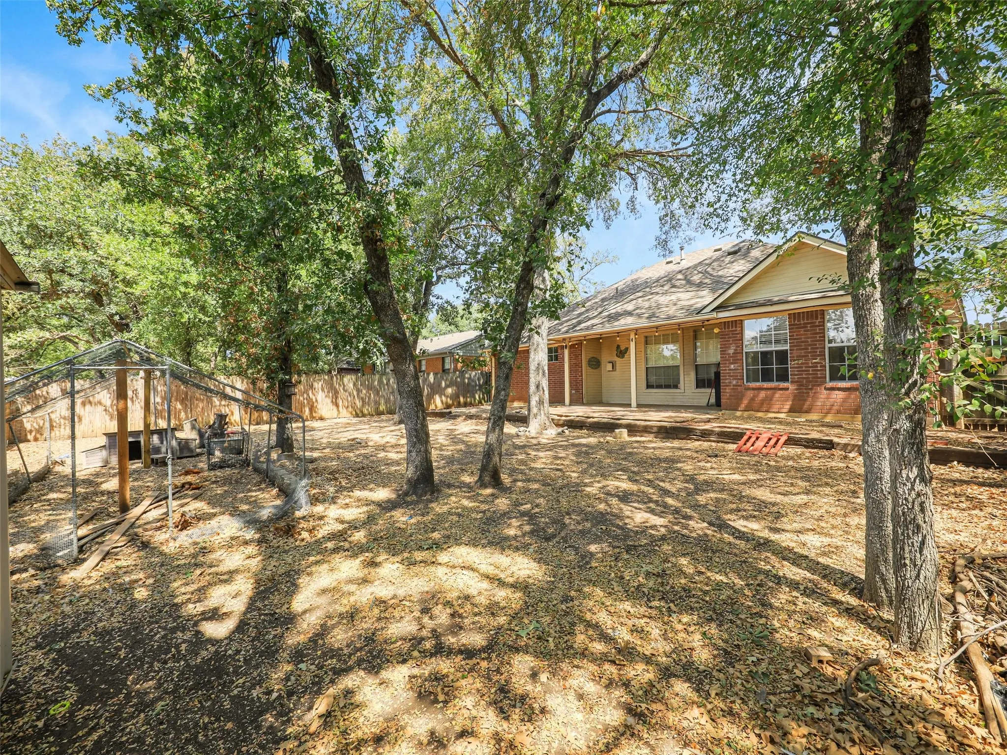 Brick exterior with natural wood shake accent, attached garage, concrete driveway, and mature trees