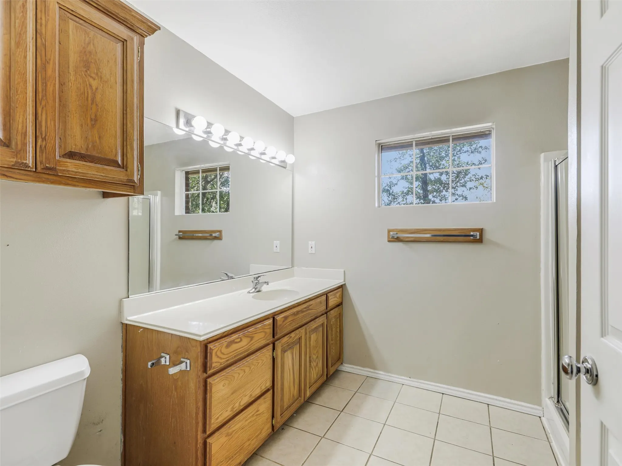 Vanity with wood-finish cabinetry, white countertop, and integrated sink