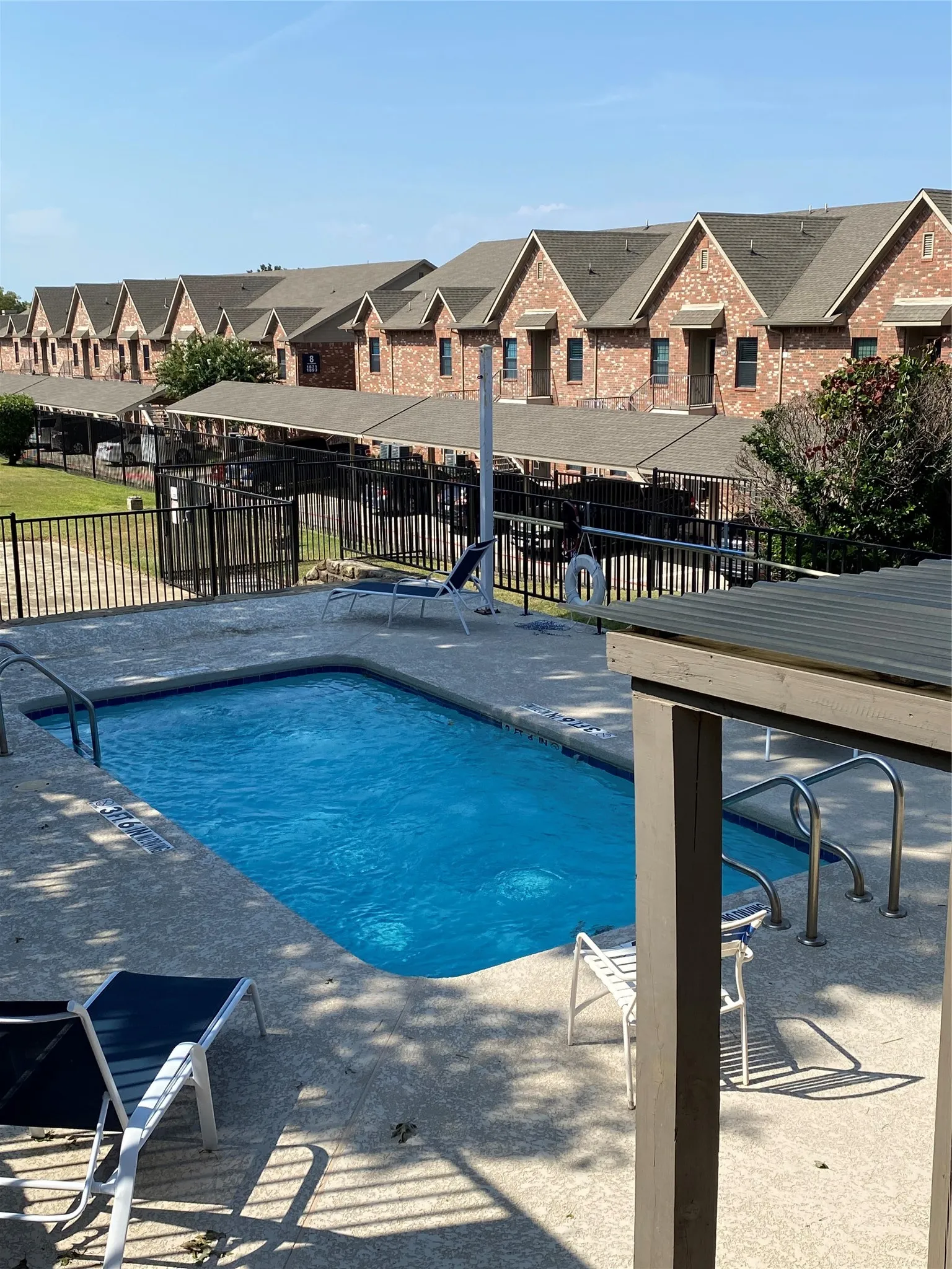 Rectangular swimming pool with integrated steps, concrete surround, and metal railing