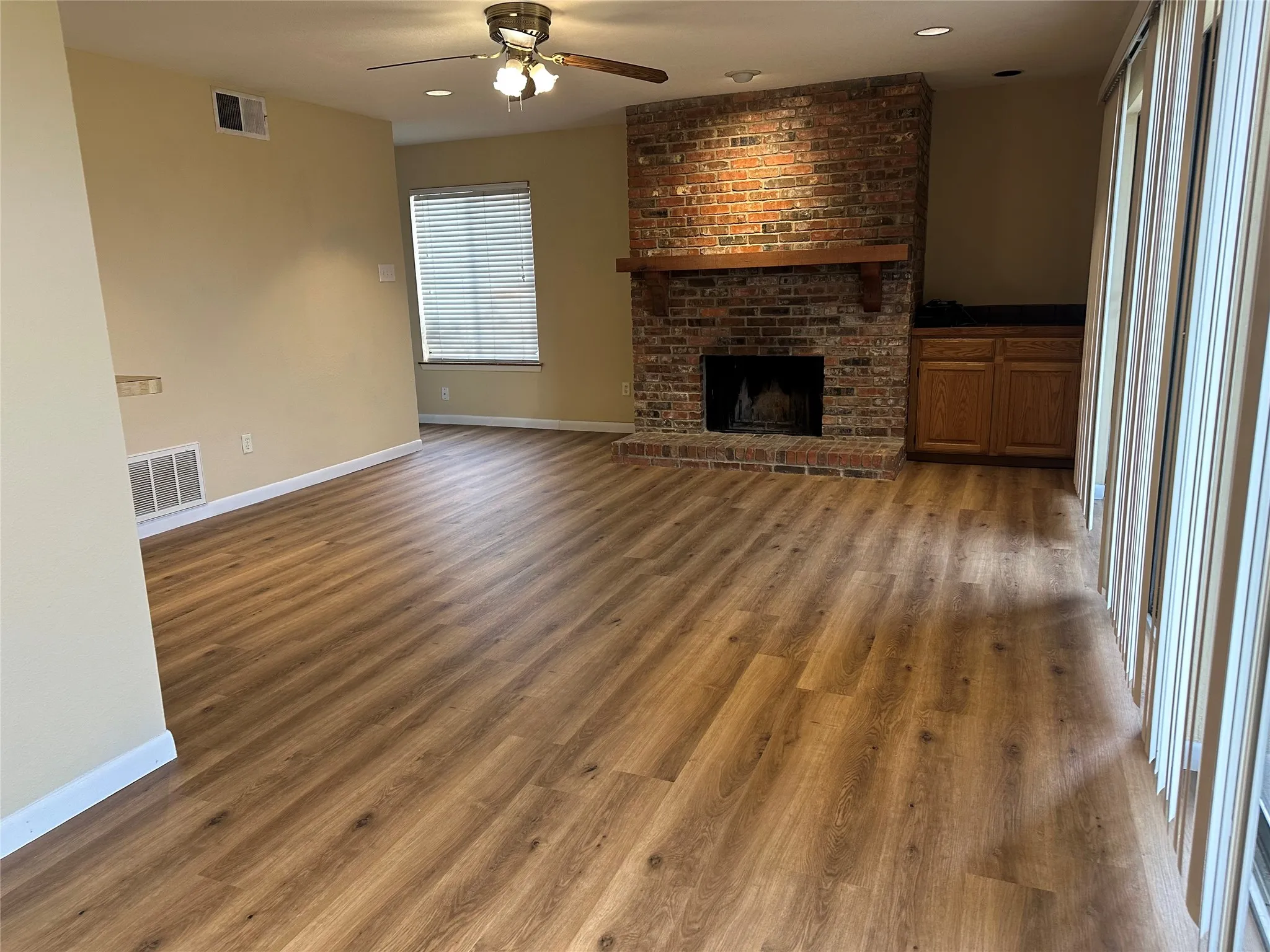 Spacious interior featuring wood-finish flooring, a brick-surround fireplace with wood mantel, and built-in cabinetry with a countertop