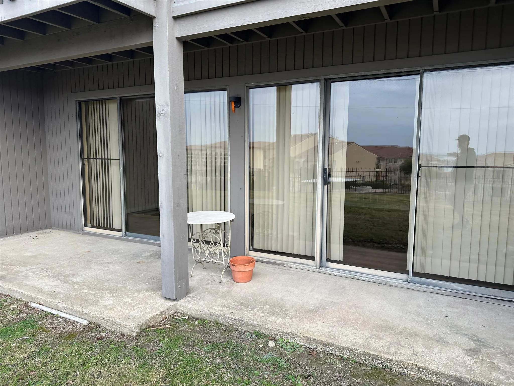 Concrete patio with multiple sliding glass doors and an exterior light fixture