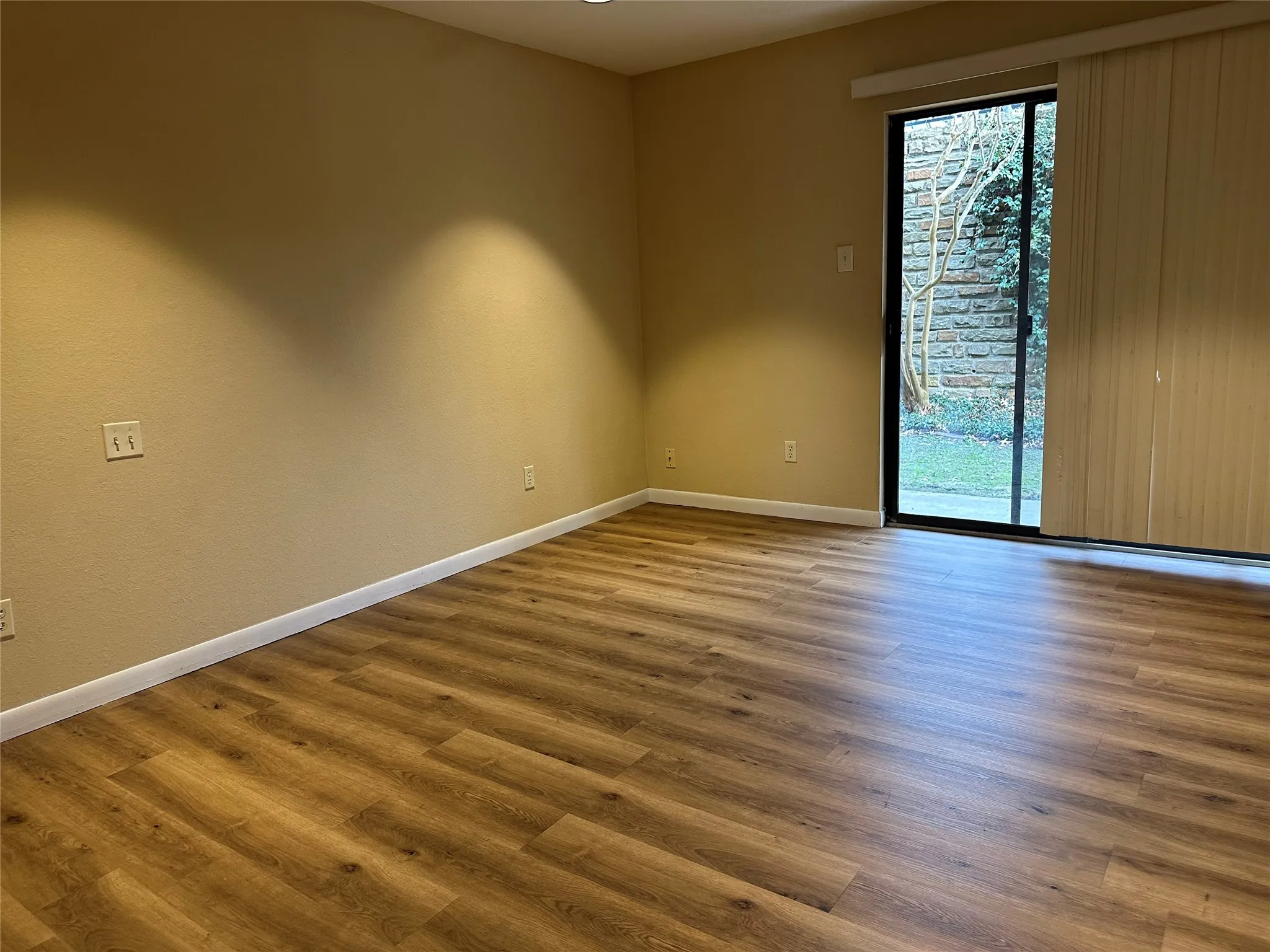 Wood-finish flooring, sliding glass door, neutral wall color, and recessed lighting
