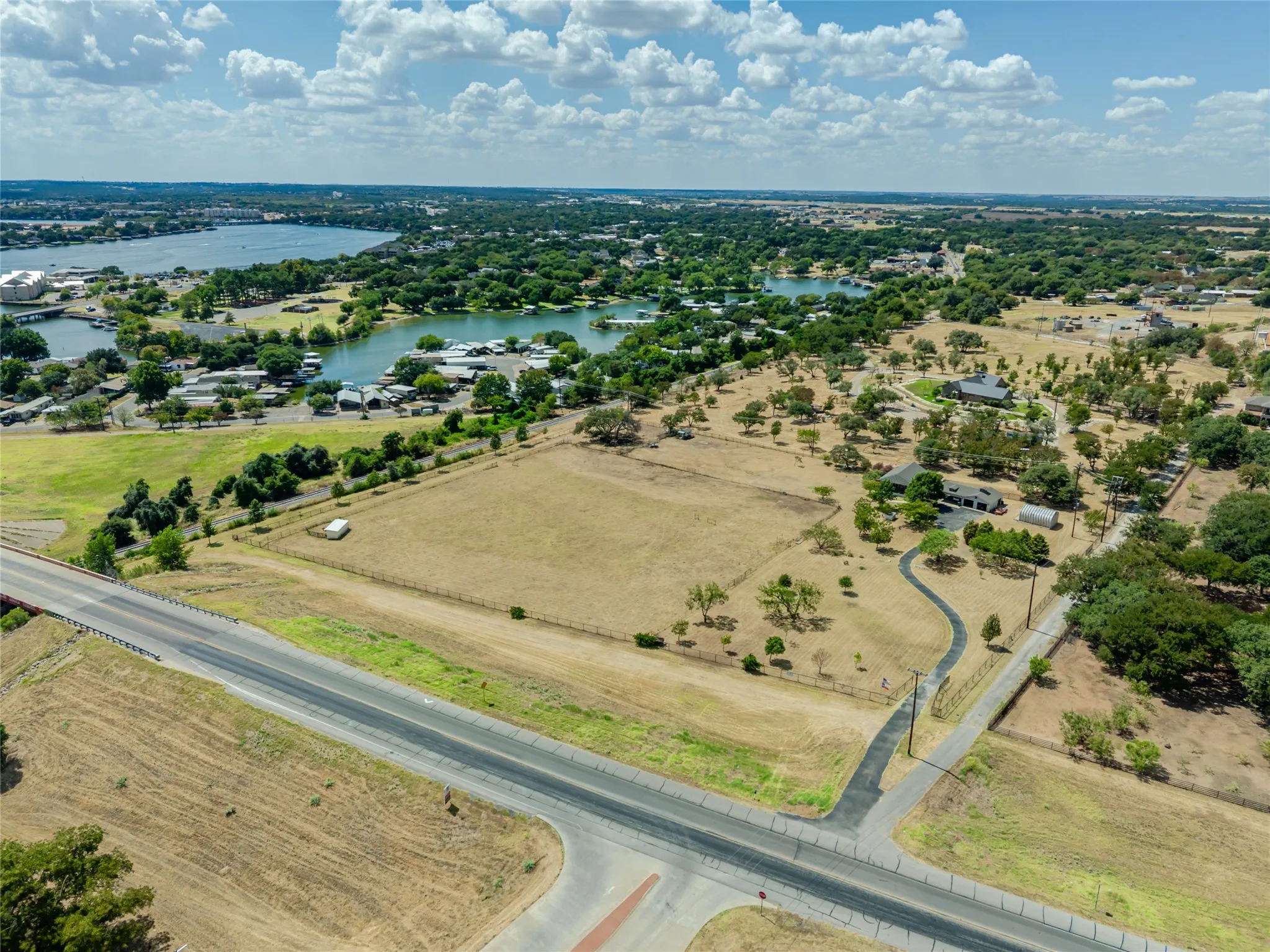 Expansive land parcel featuring a private driveway, scattered mature trees, and a perimeter fence